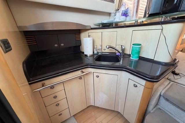 2004 Sea Ray 420 Sedan Bridge kitchen with sleek black countertops and modern cabinetry.