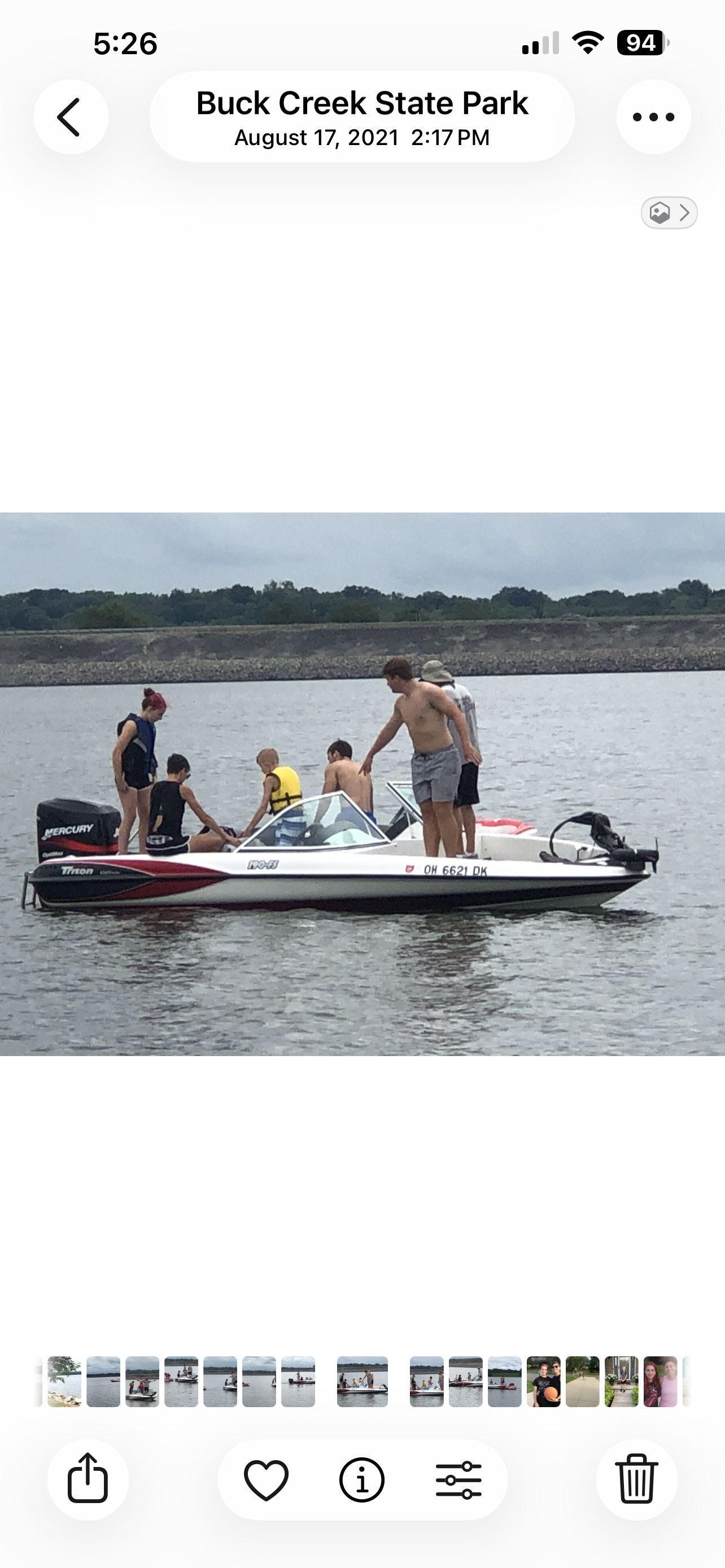 A group of people stands on a white boat on a lake.