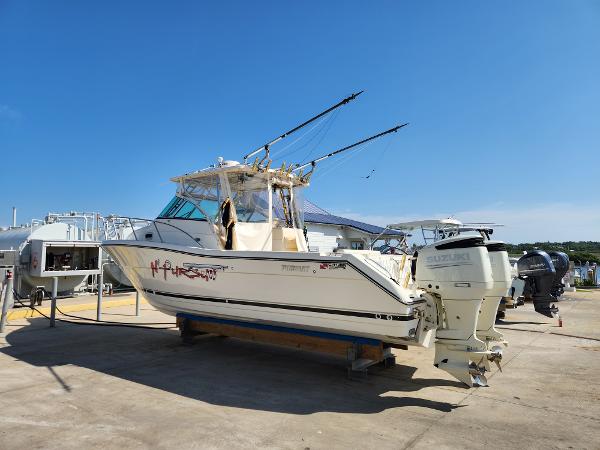 2005 Pursuit 3070 Offshore Center Console boat on dry dock with dual Suzuki engines.
