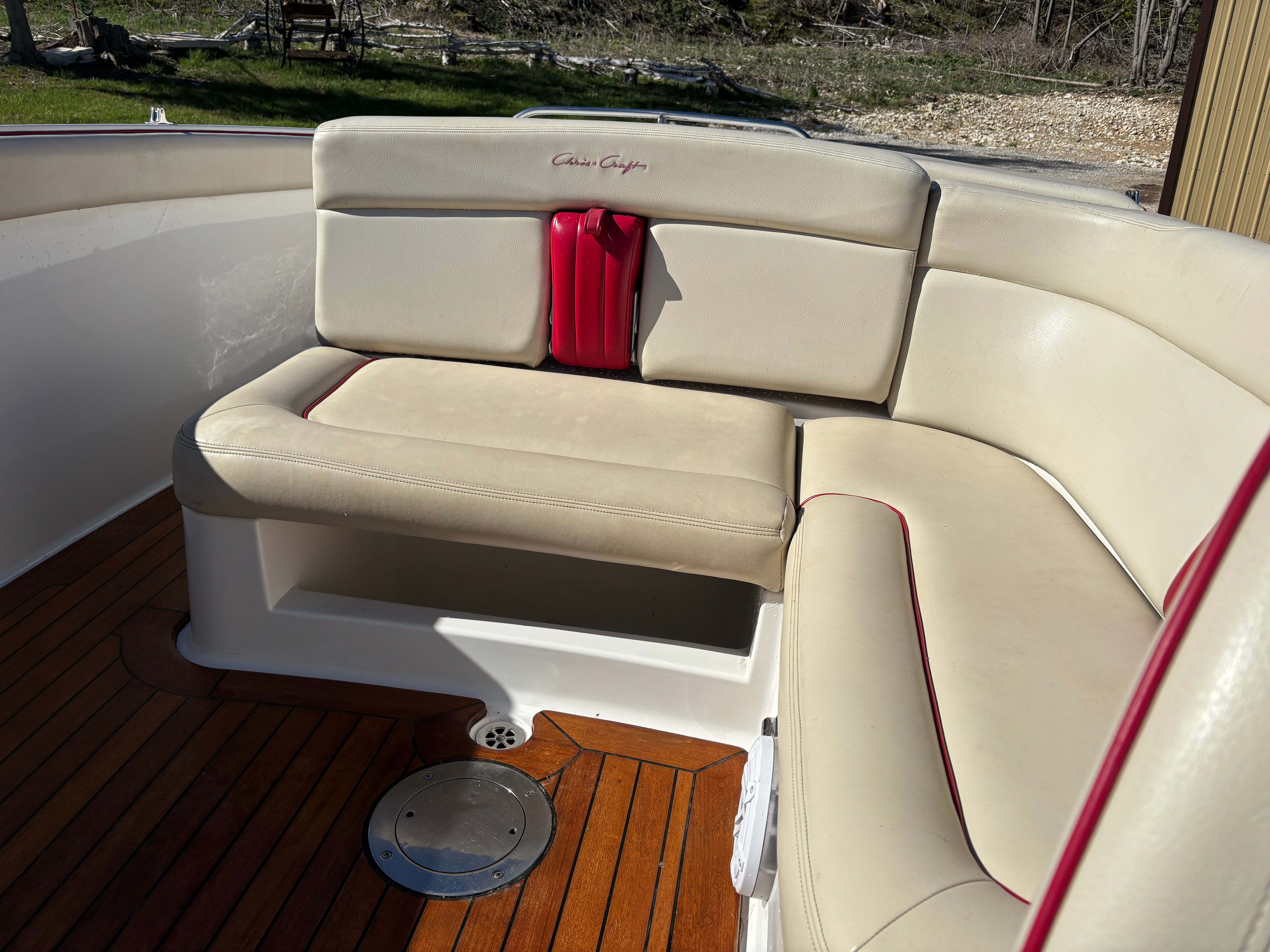 Interior of a Chris-Craft Launch 22 boat with beige seating and wooden flooring.