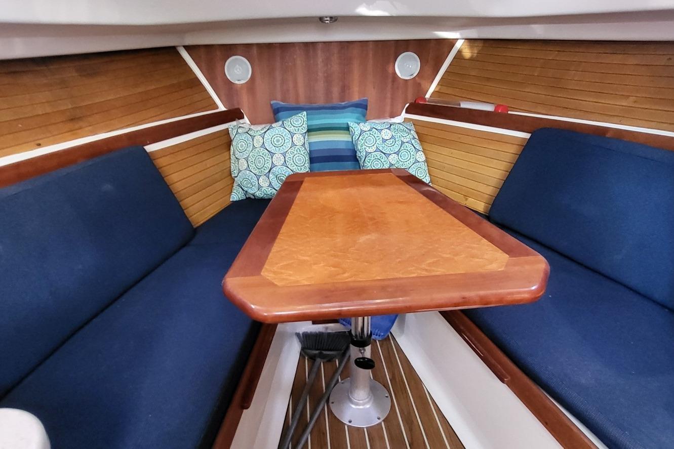 Interior of 2006 Back Cove 29 boat with wooden table and blue seating.