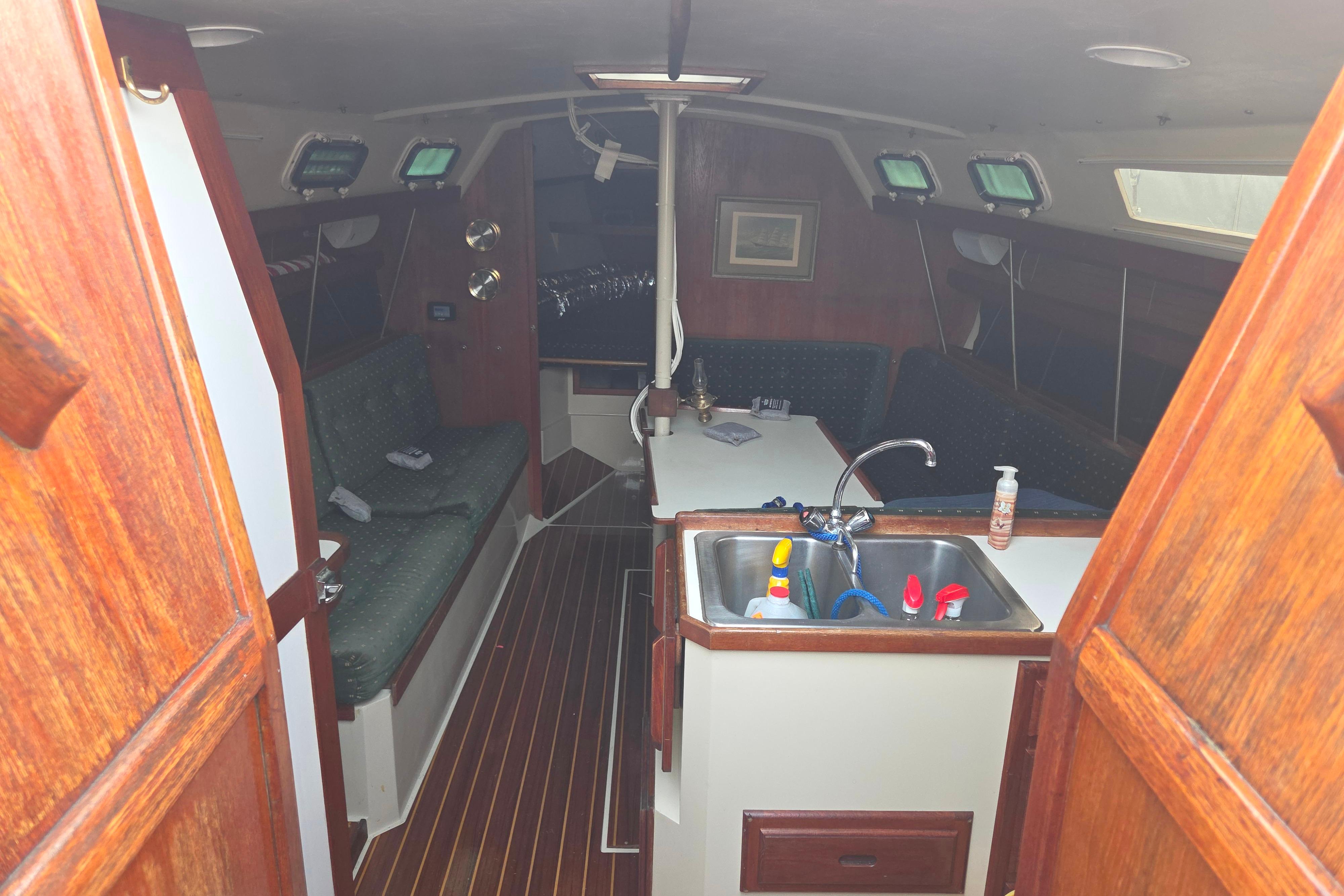 Interior of a 1986 Catalina 355 sailboat with wooden finishes and compact kitchen area.
