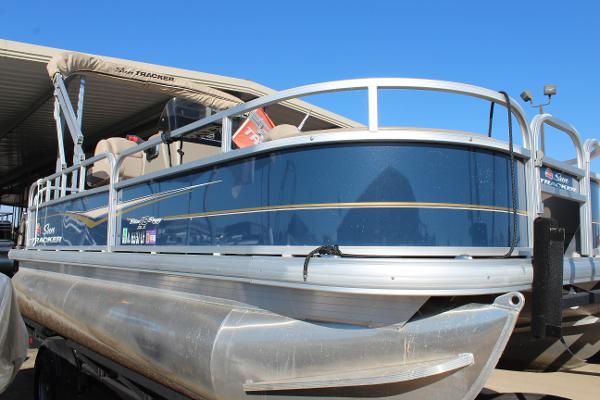 2024 Sun Tracker BB18 pontoon boat with blue exterior, docked under clear sky.