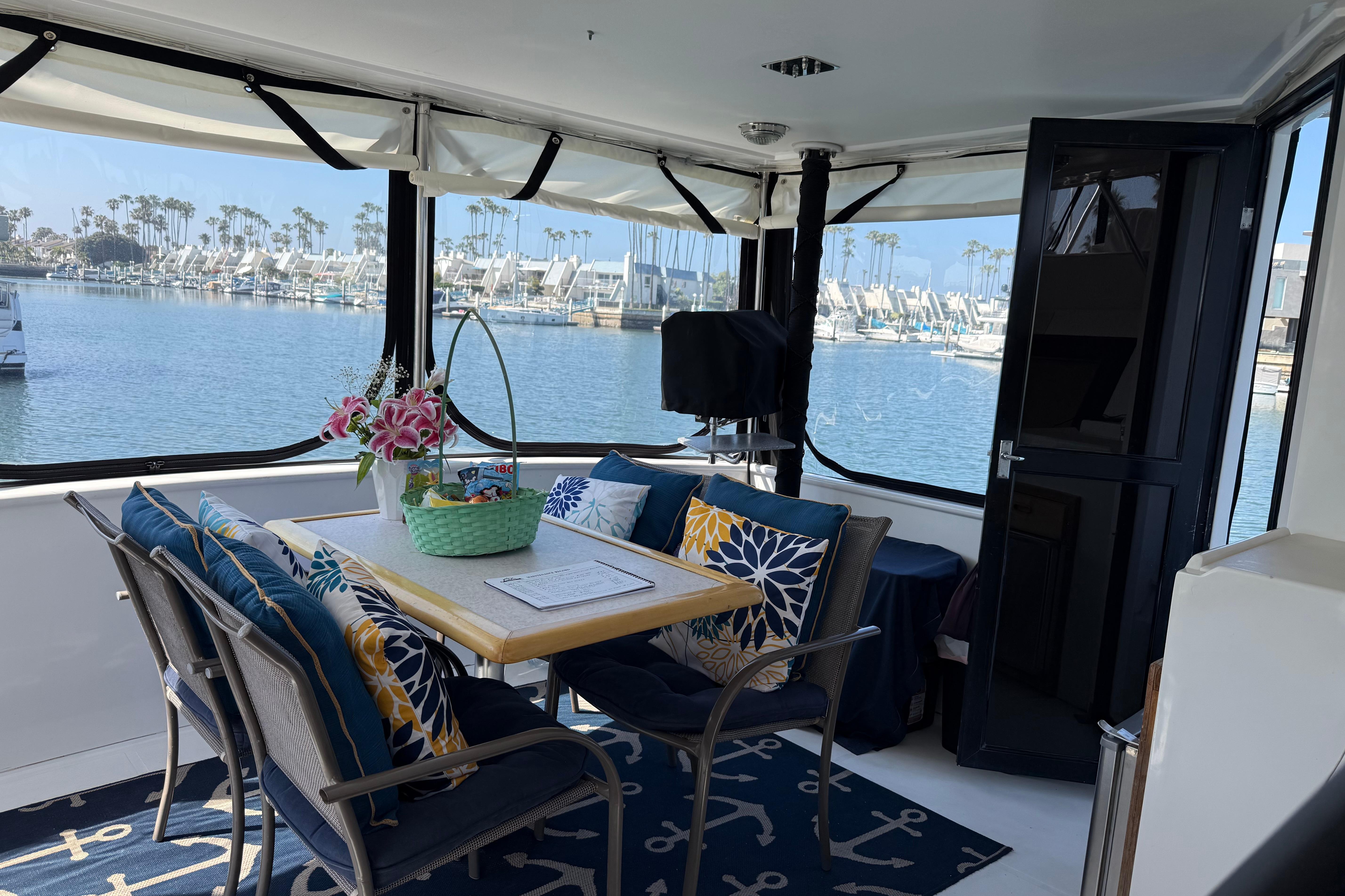 Cozy interior of 1993 Novatec 44 yacht with marina view, featuring a dining area and decorative pillows.