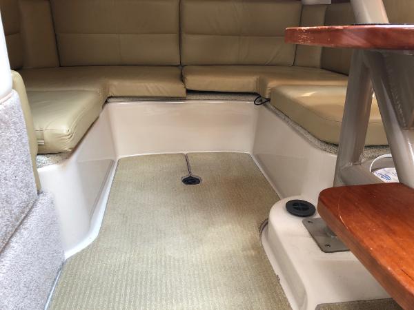 Interior of a 2008 Four Winns V338 with beige upholstery and a wooden table.