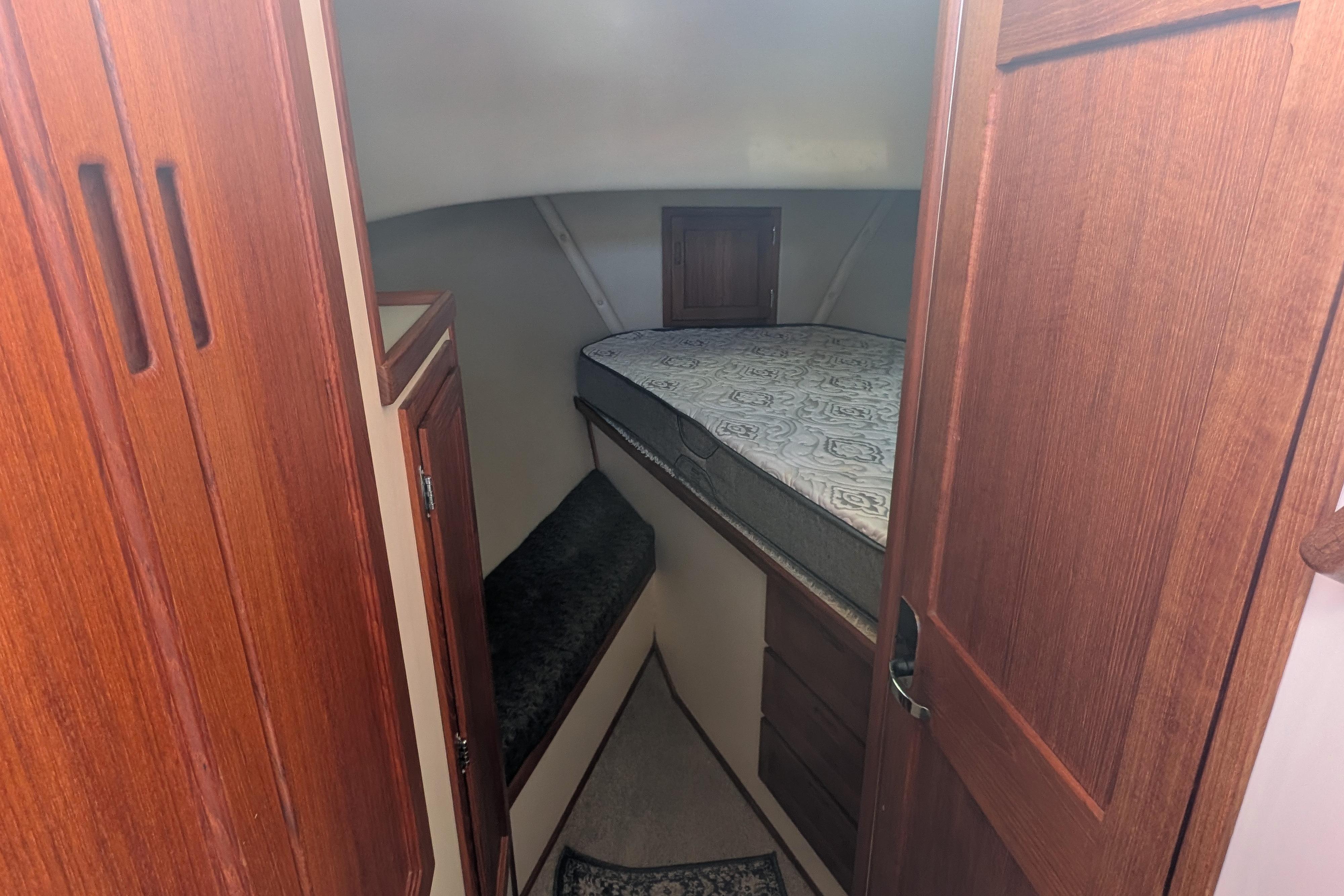 Cozy cabin interior of a 1998 Nordic Tug 32 with wooden cabinetry and a comfortable bed.