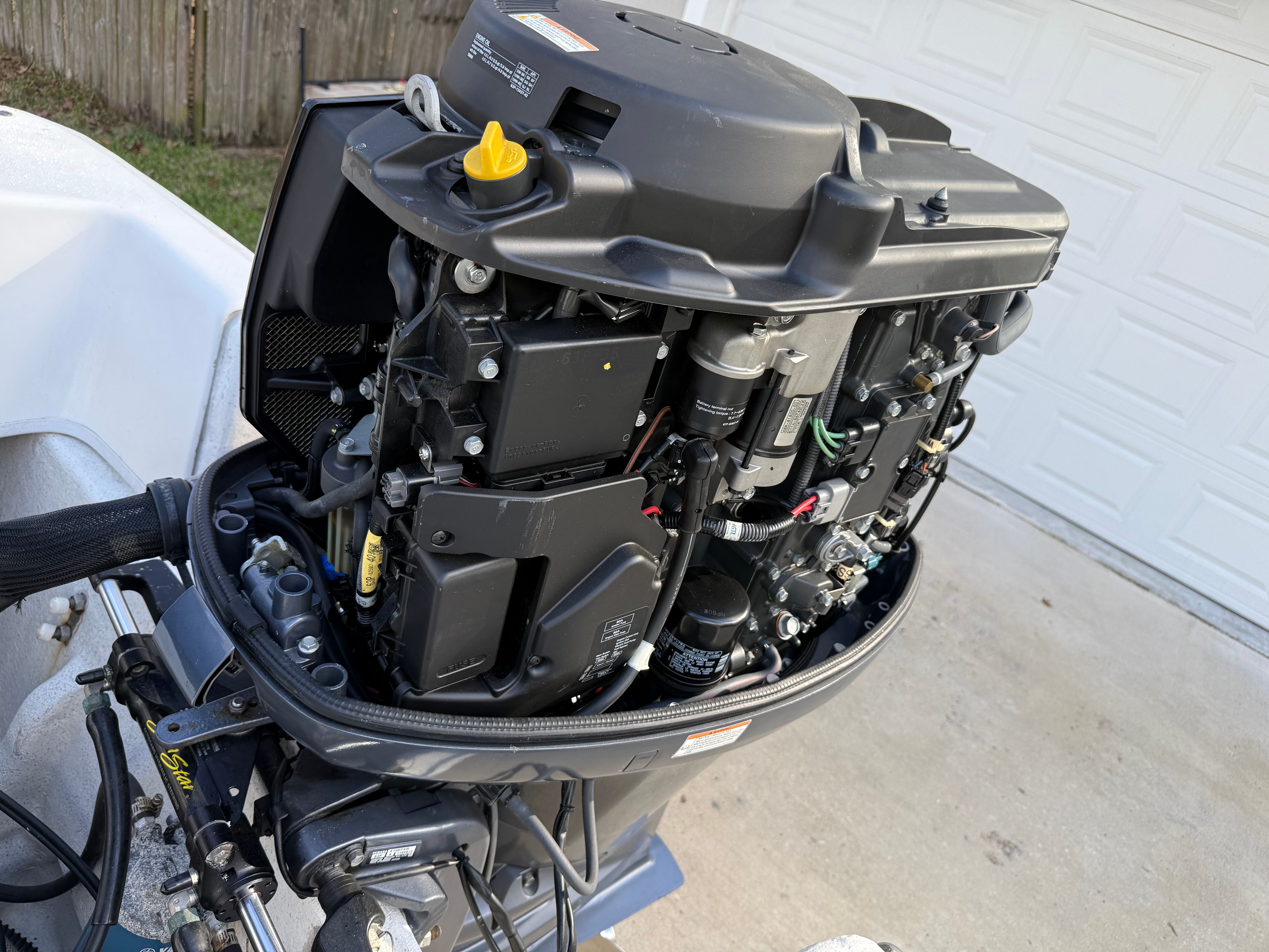 An outboard motor with its cover removed, revealing internal components and wiring.