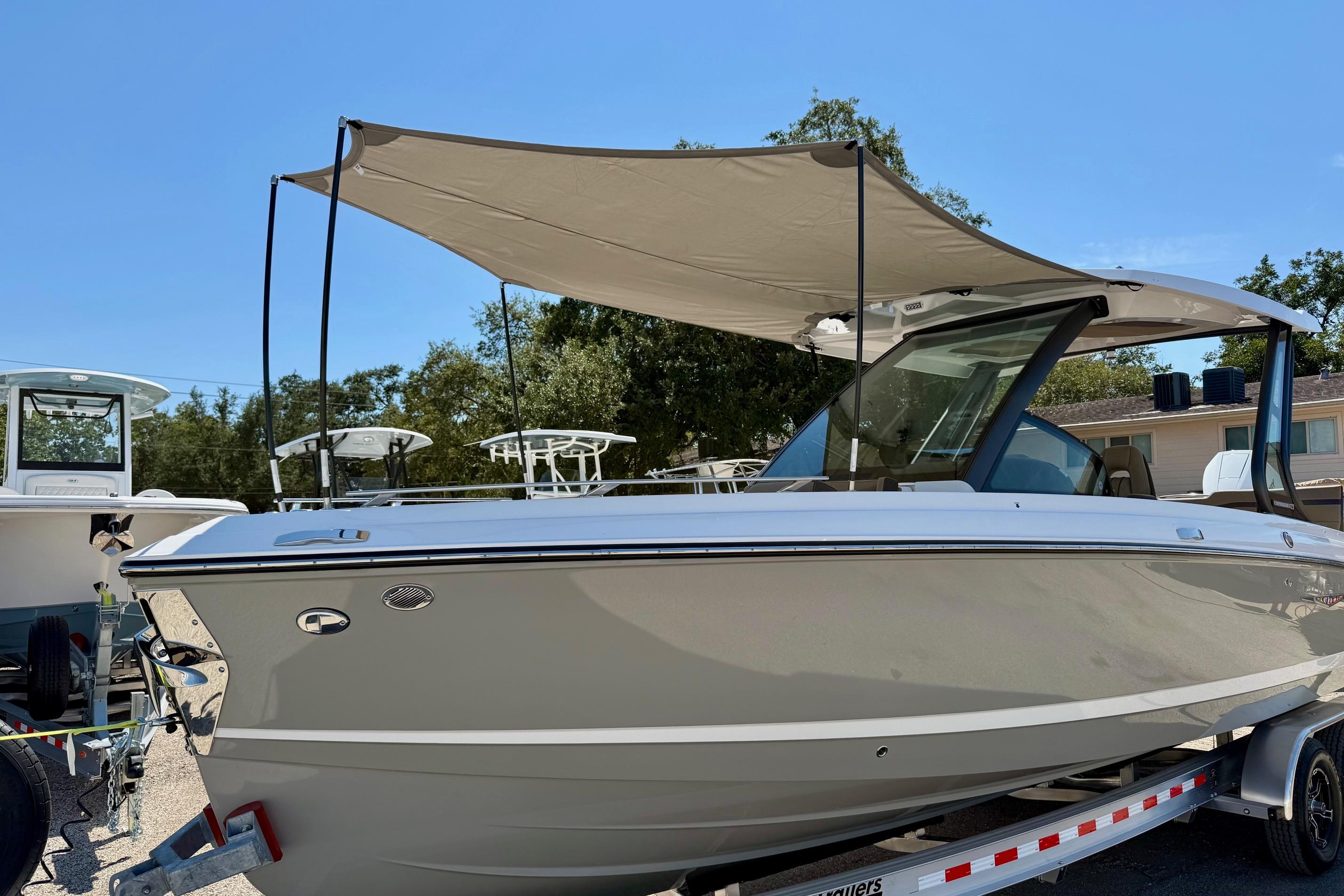 2026 Monterey Elite 27 OB boat with canopy on trailer, parked outdoors.