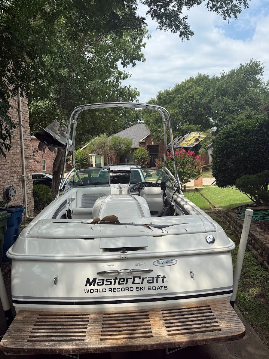 A 1999 MasterCraft Prostar 205 is parked in a driveway. It features an open interior and a tower.