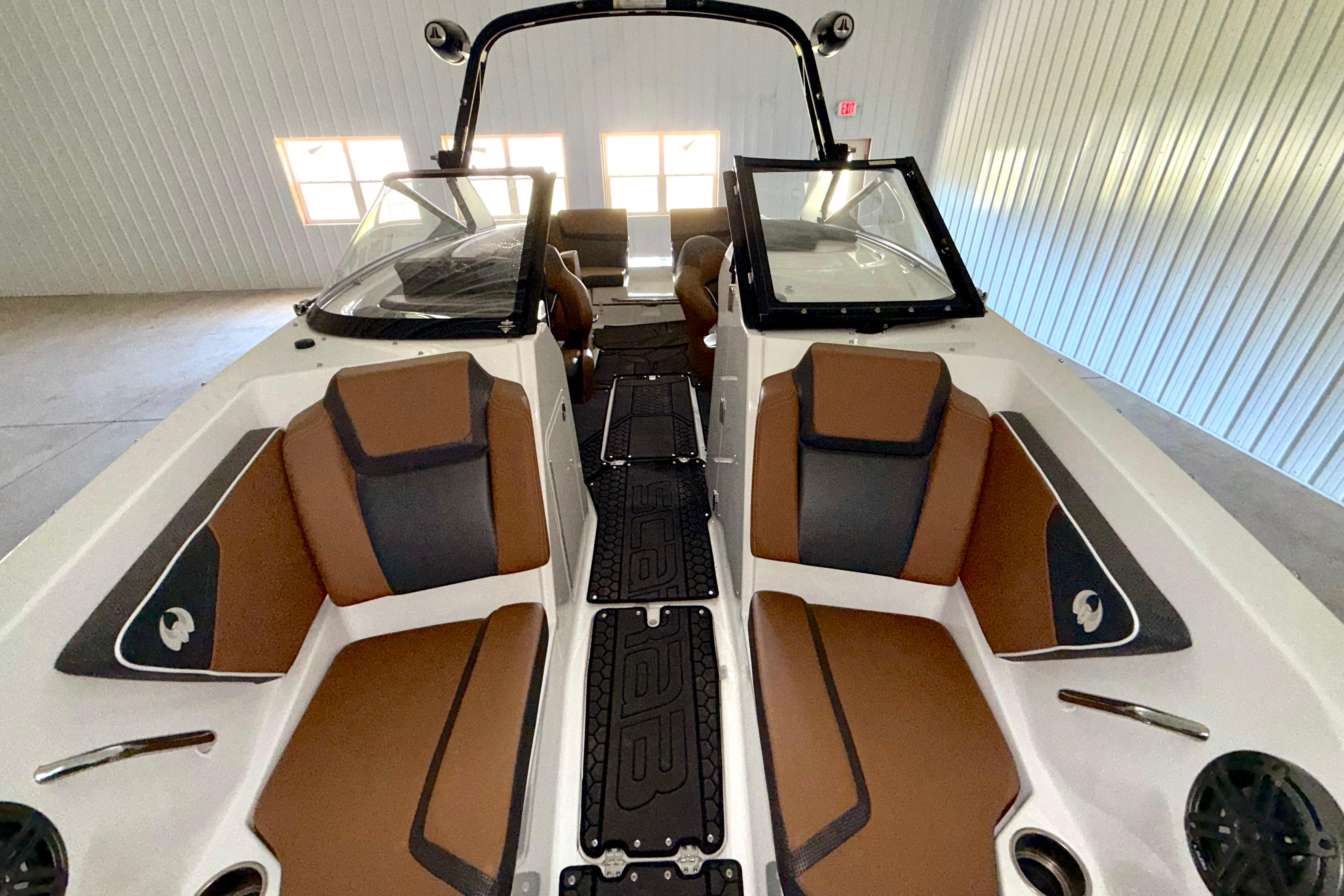 2023 Scarab 255 ID boat interior with brown and black seating in a garage.