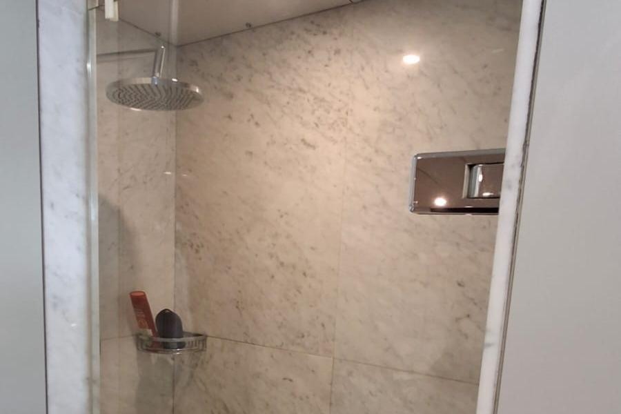Marble-tiled shower with modern fixtures on a 1960 Clelands Shipbuilding TSDMY.