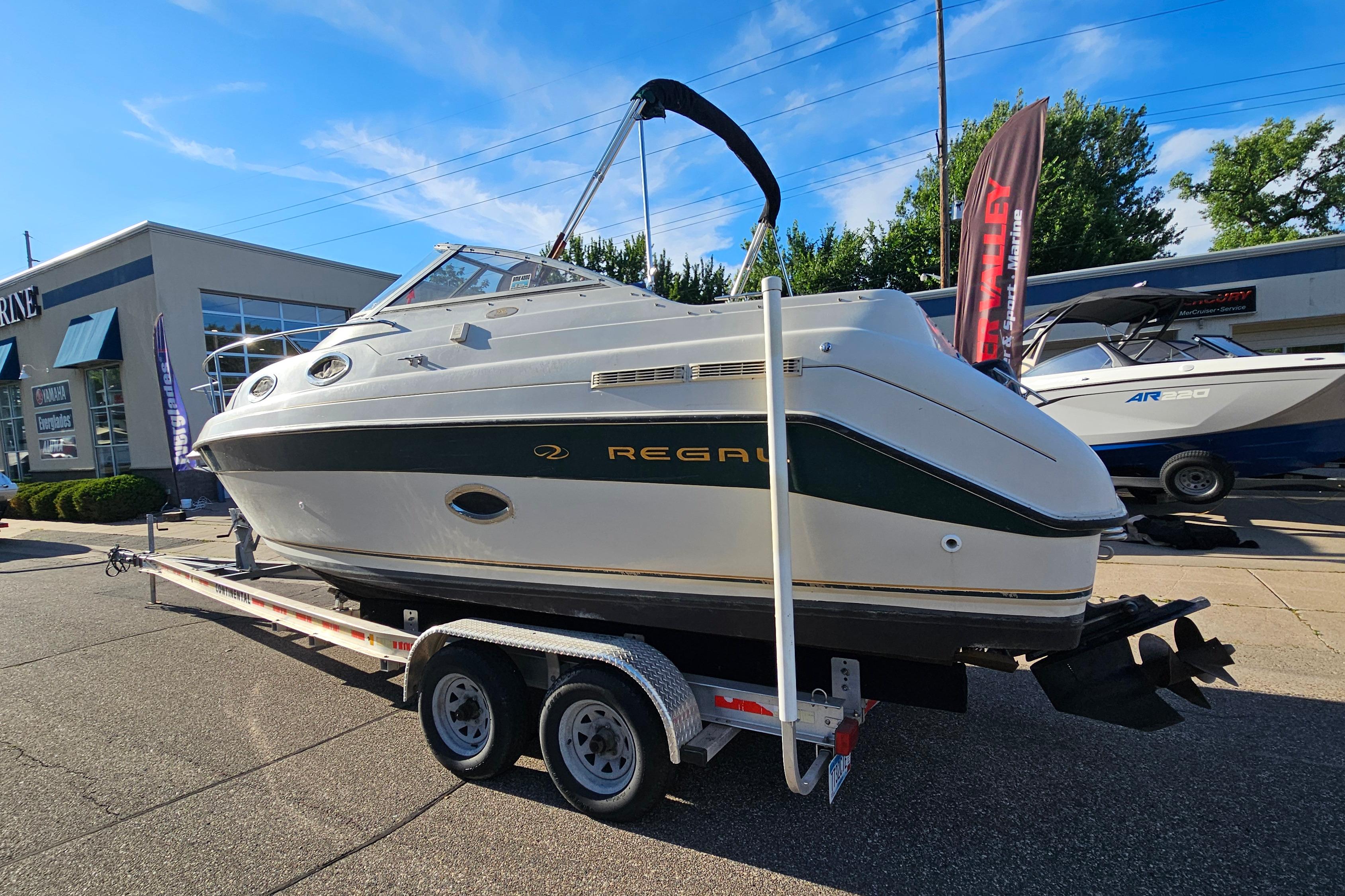 1999 Regal Commodore 258 boat on trailer, displayed outdoors at a dealership.