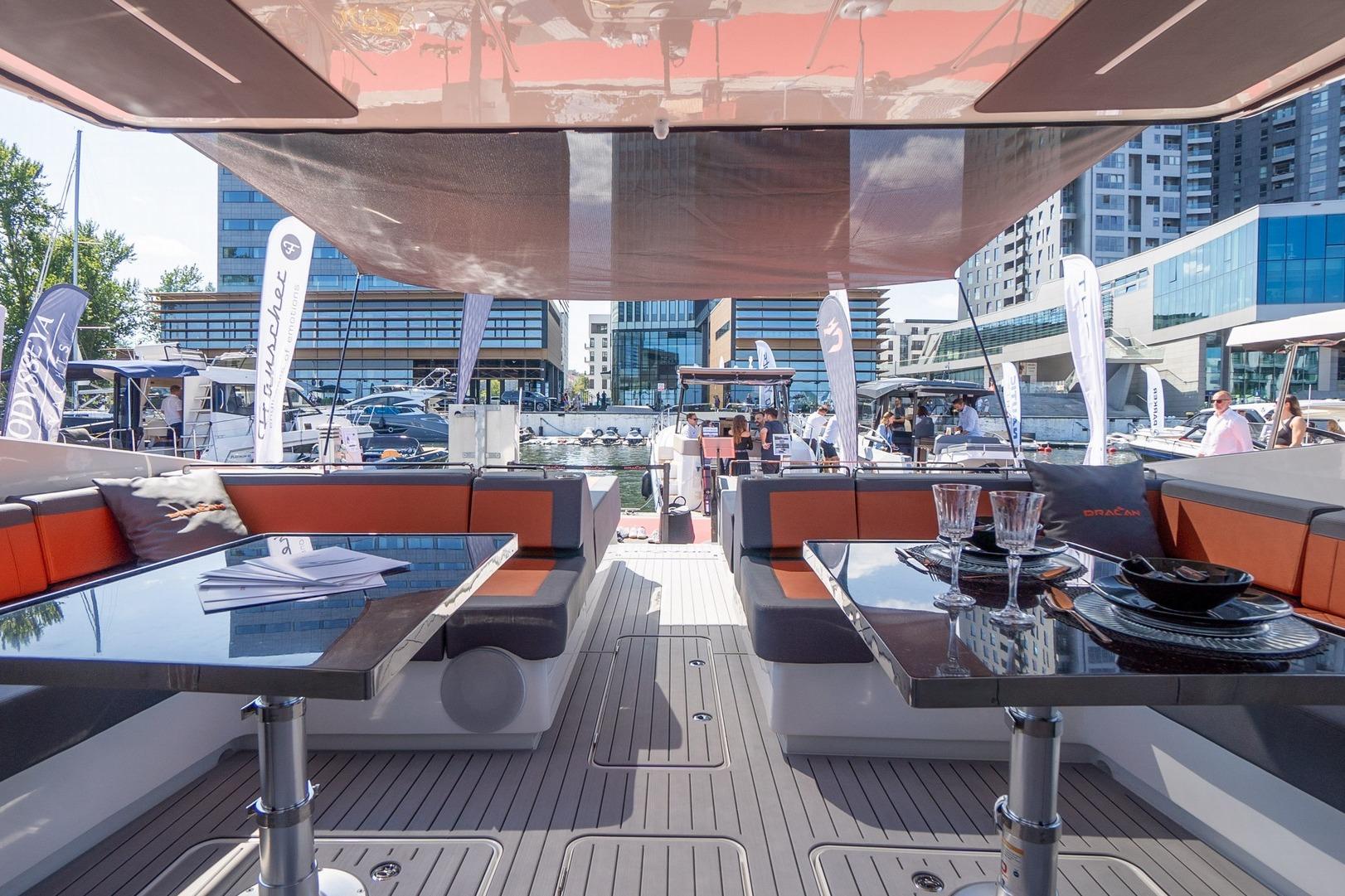 Luxurious 2026 Dracan 42 Catamaran interior with elegant seating and dining area at a marina.