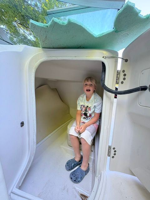 A child sits in a small boat cabin area.