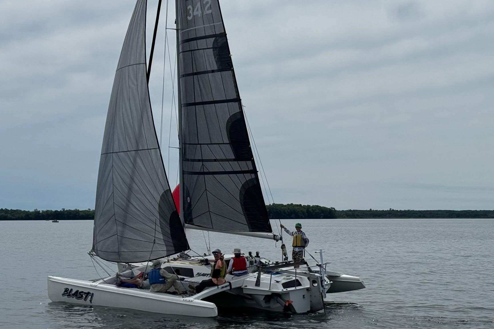 Sailing on a 1993 Corsair F-27 trimaran with black sails on a calm lake.