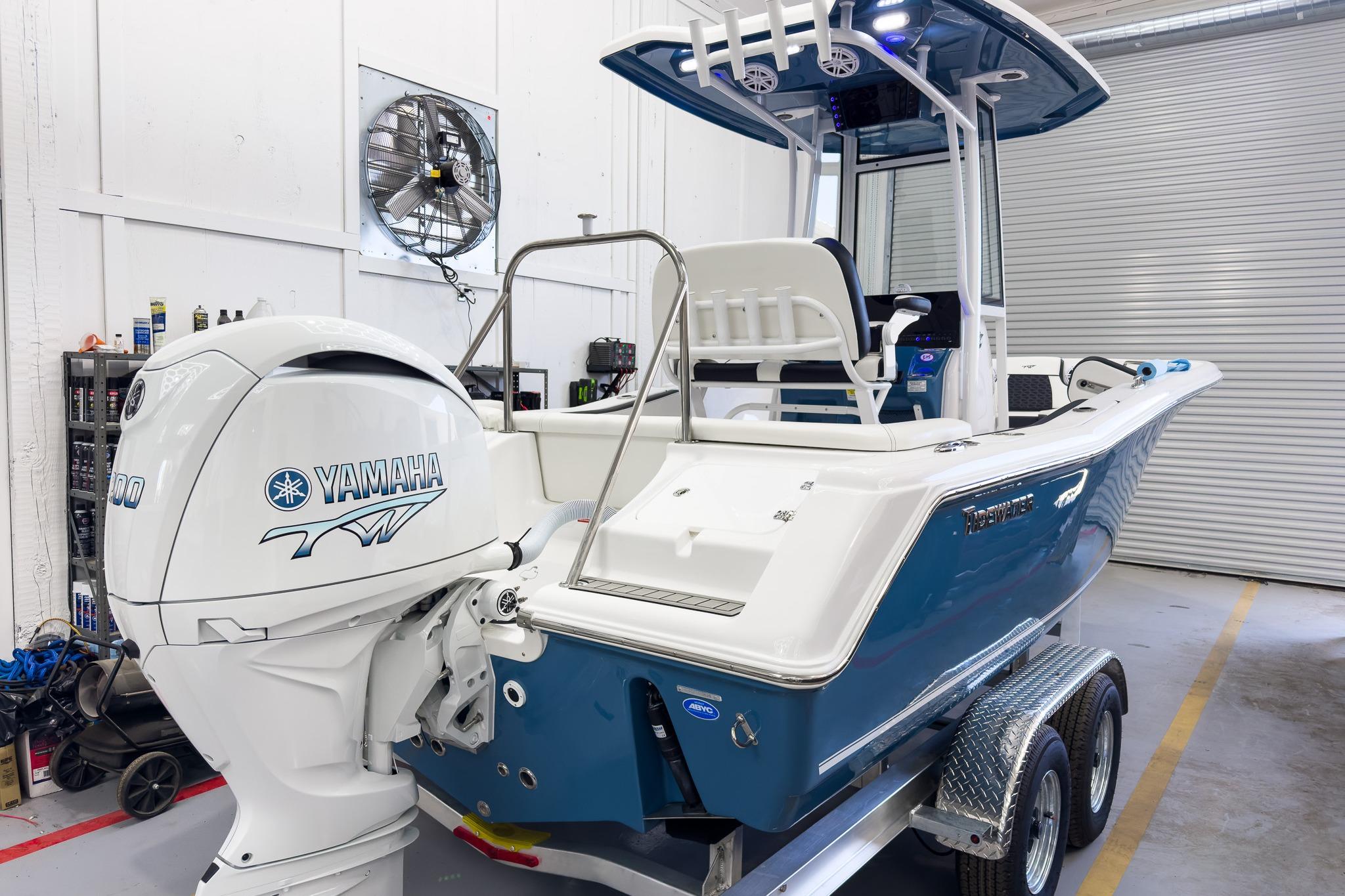 A 2026 Tidewater 220 LXF boat in a garage on a trailer, featuring a Yamaha outboard motor.