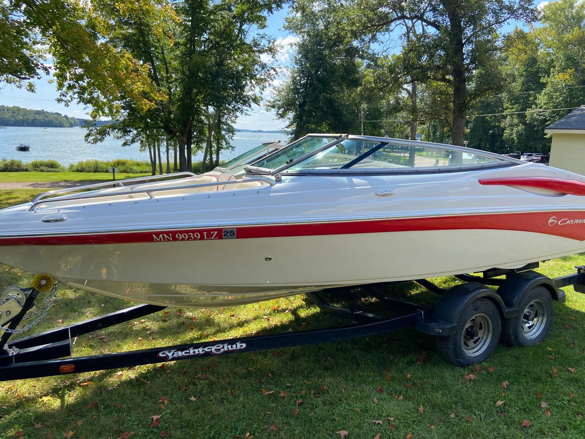 A 2011 Crownline 21 SS boat on a trailer in a green, scenic setting.