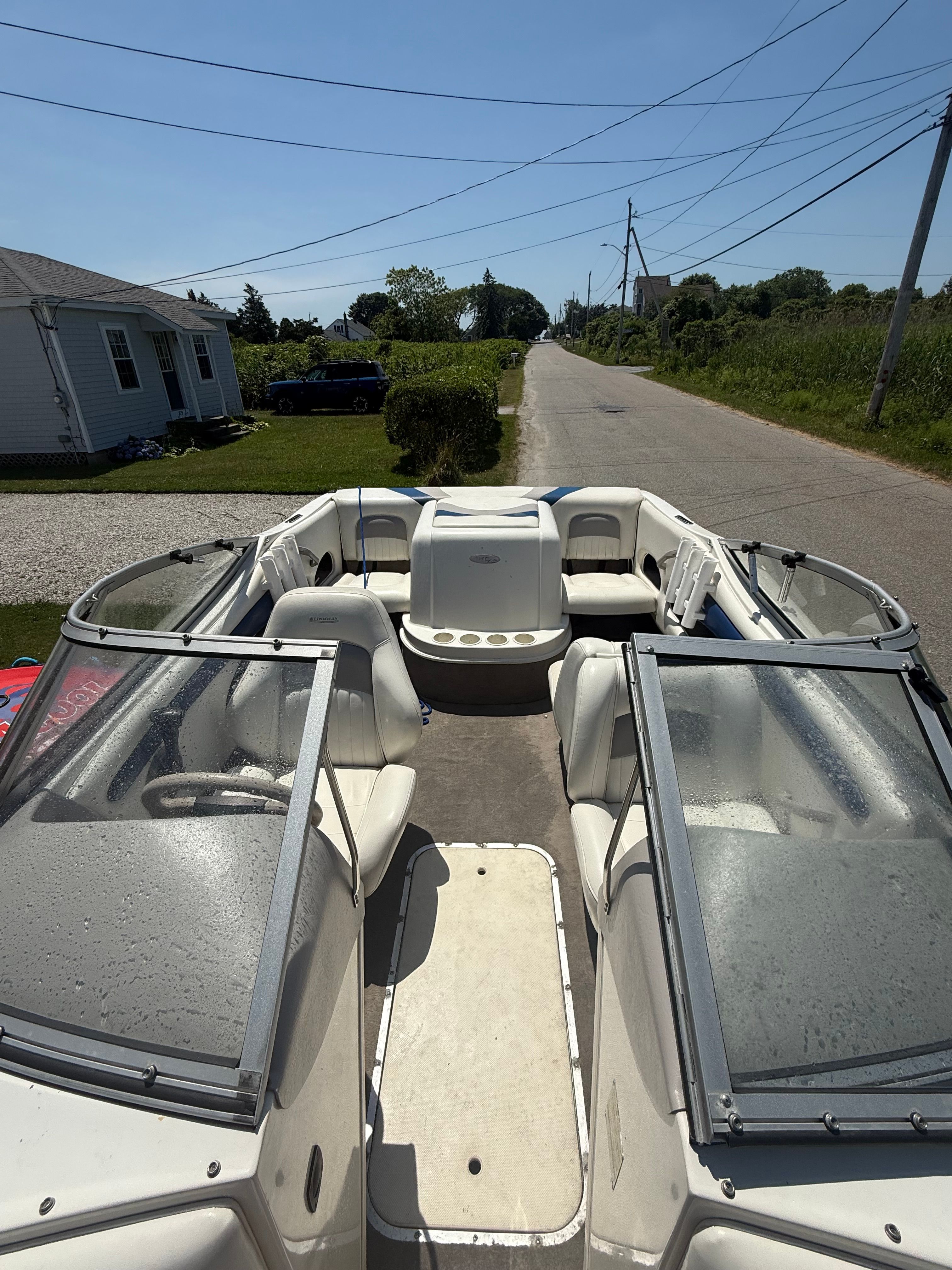A 2003 Stingray 180 LS/LX boat is on a trailer on a rural road.