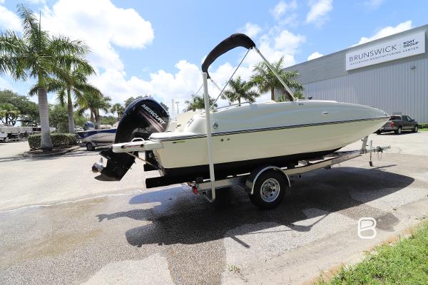 2018 Bayliner 210 DB boat on trailer, parked outdoors near palm trees and a building.