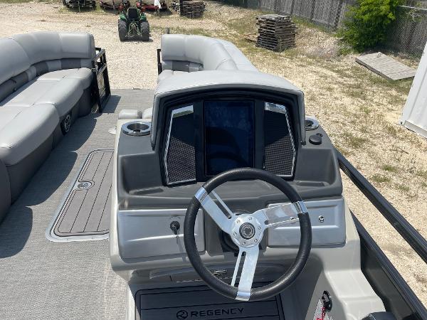 2023 Regency 250 LE3 boat interior with steering wheel and seating area.
