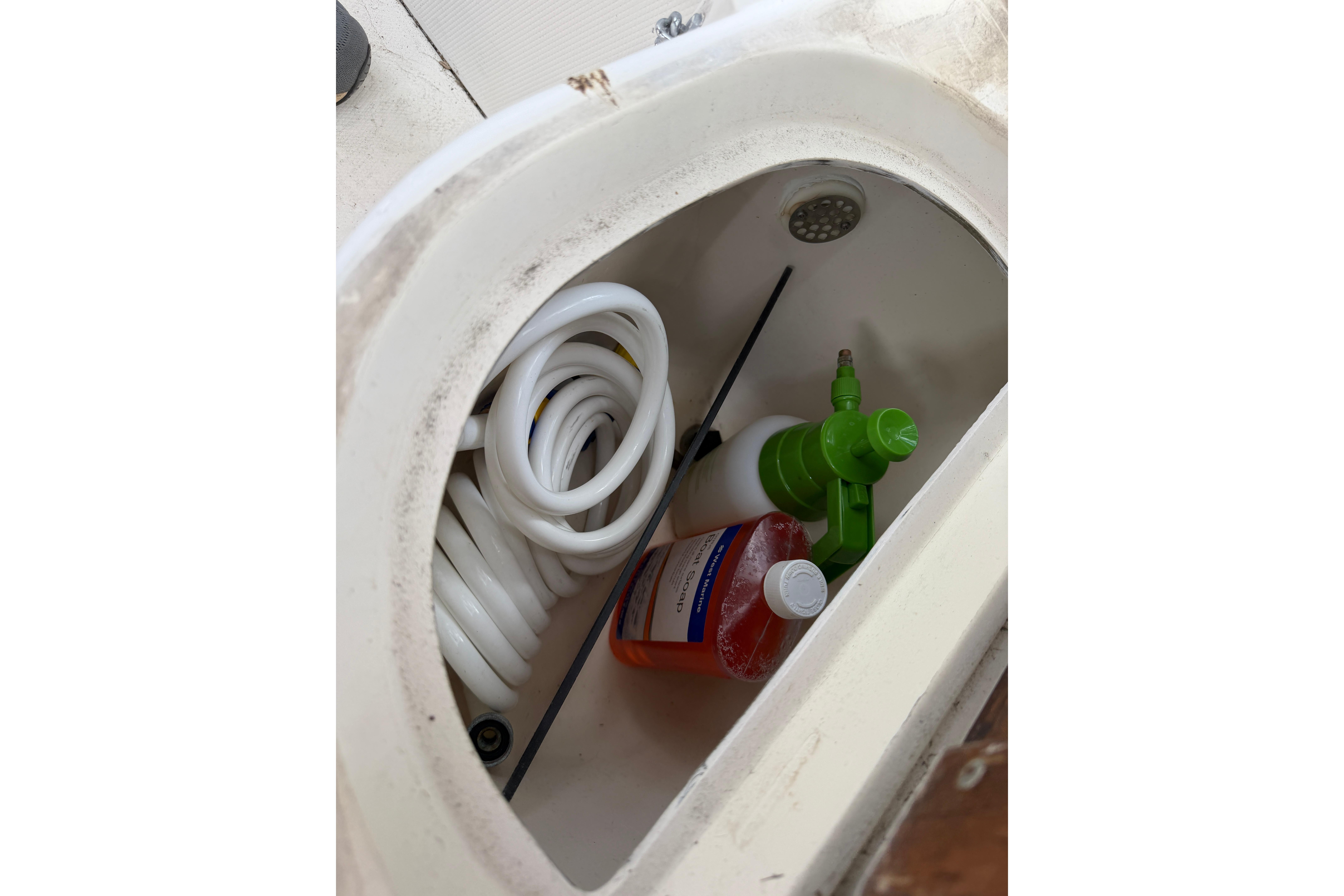 Storage compartment in a 1987 Grady-White Seafarer 226 with hose and cleaning supplies.
