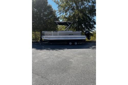 2026 Sun Tracker Fishin' Barge 22 DLX pontoon boat parked outdoors.