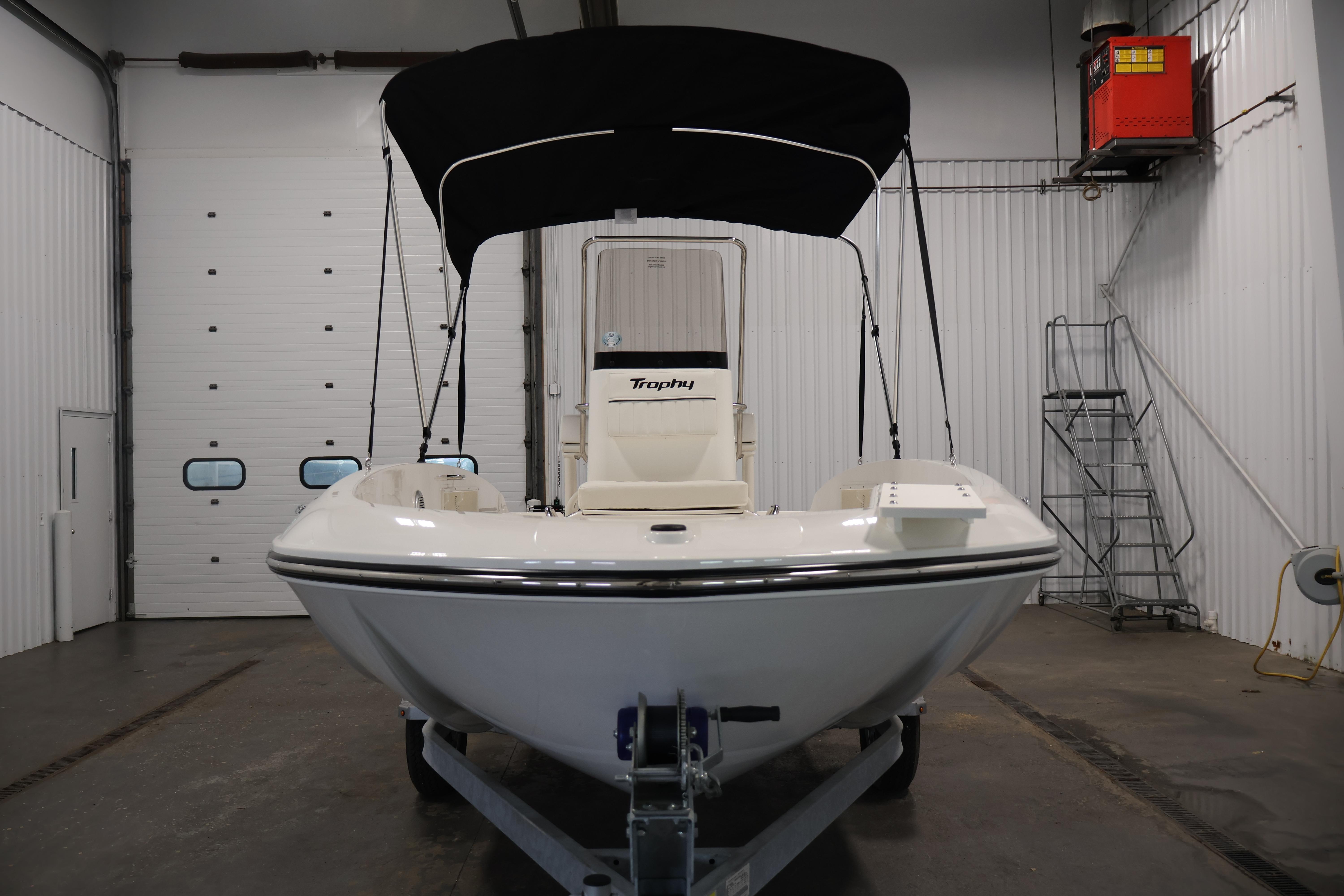 2026 Bayliner Trophy T18 boat in a garage, featuring a sleek design and black canopy.