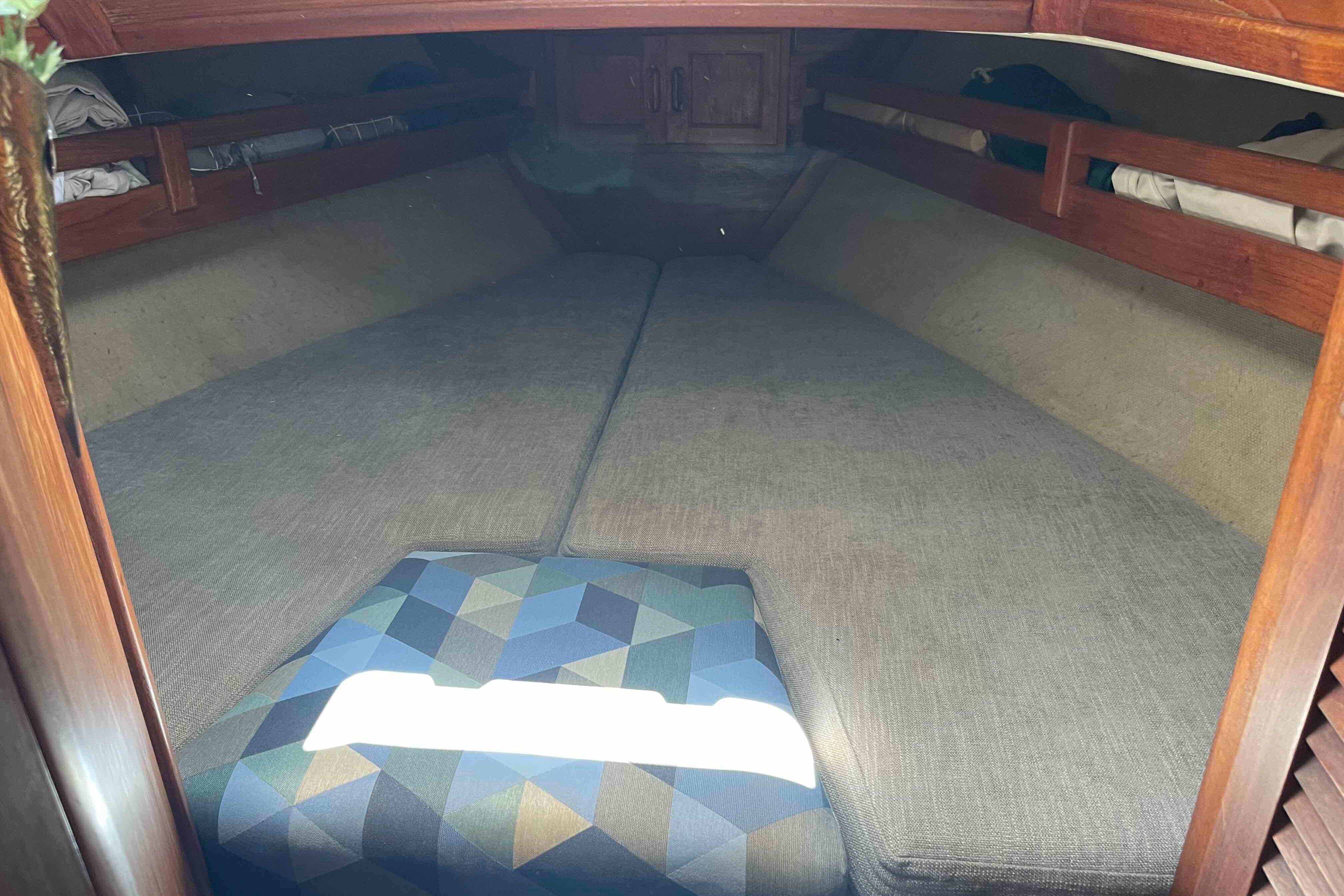 1987 Pacific Seacraft 34 interior cabin with cushioned sleeping area and wooden storage.