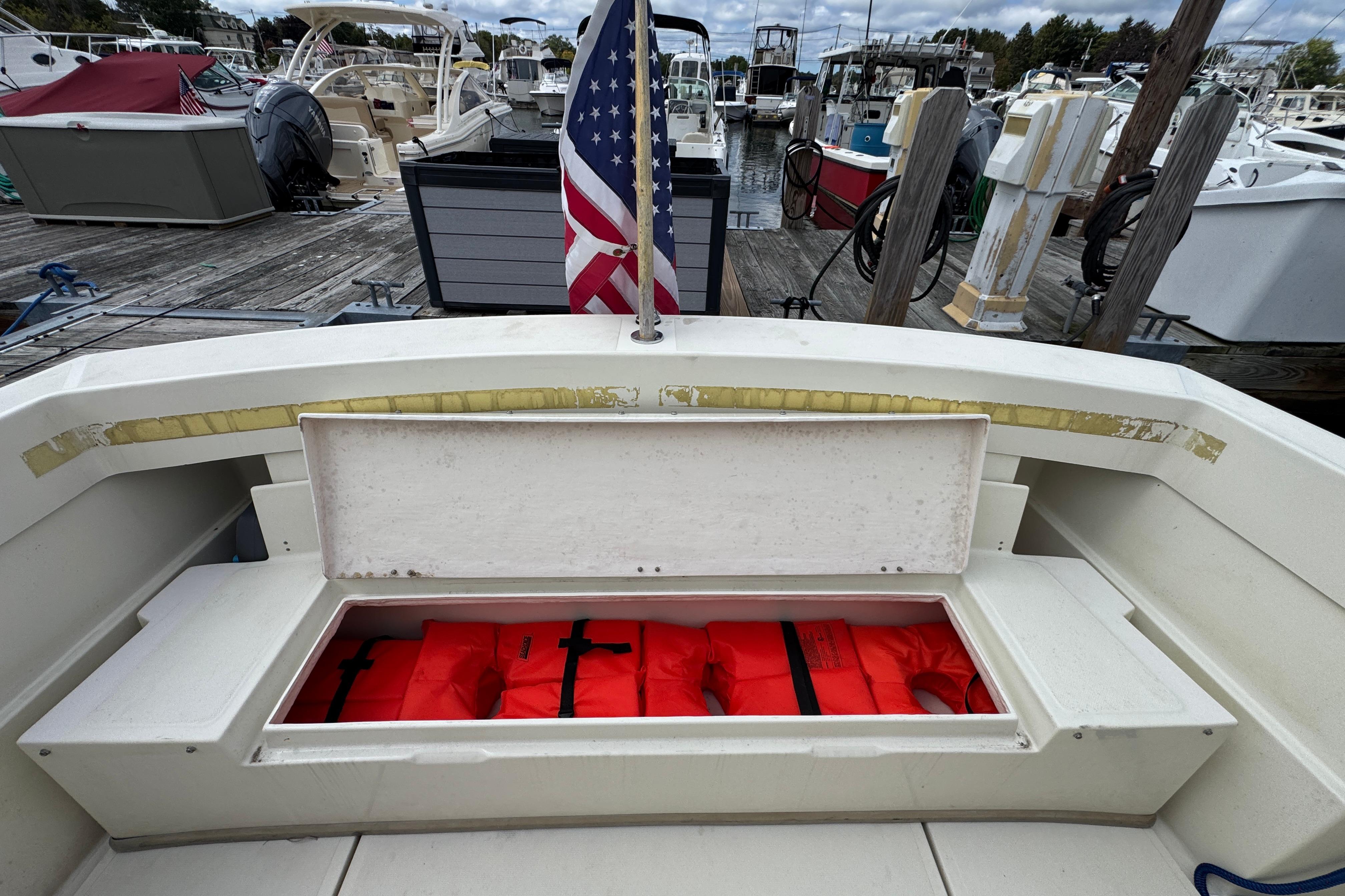 2006 Limestone 26 boat with open storage compartment, red life jackets, and American flag at marina.