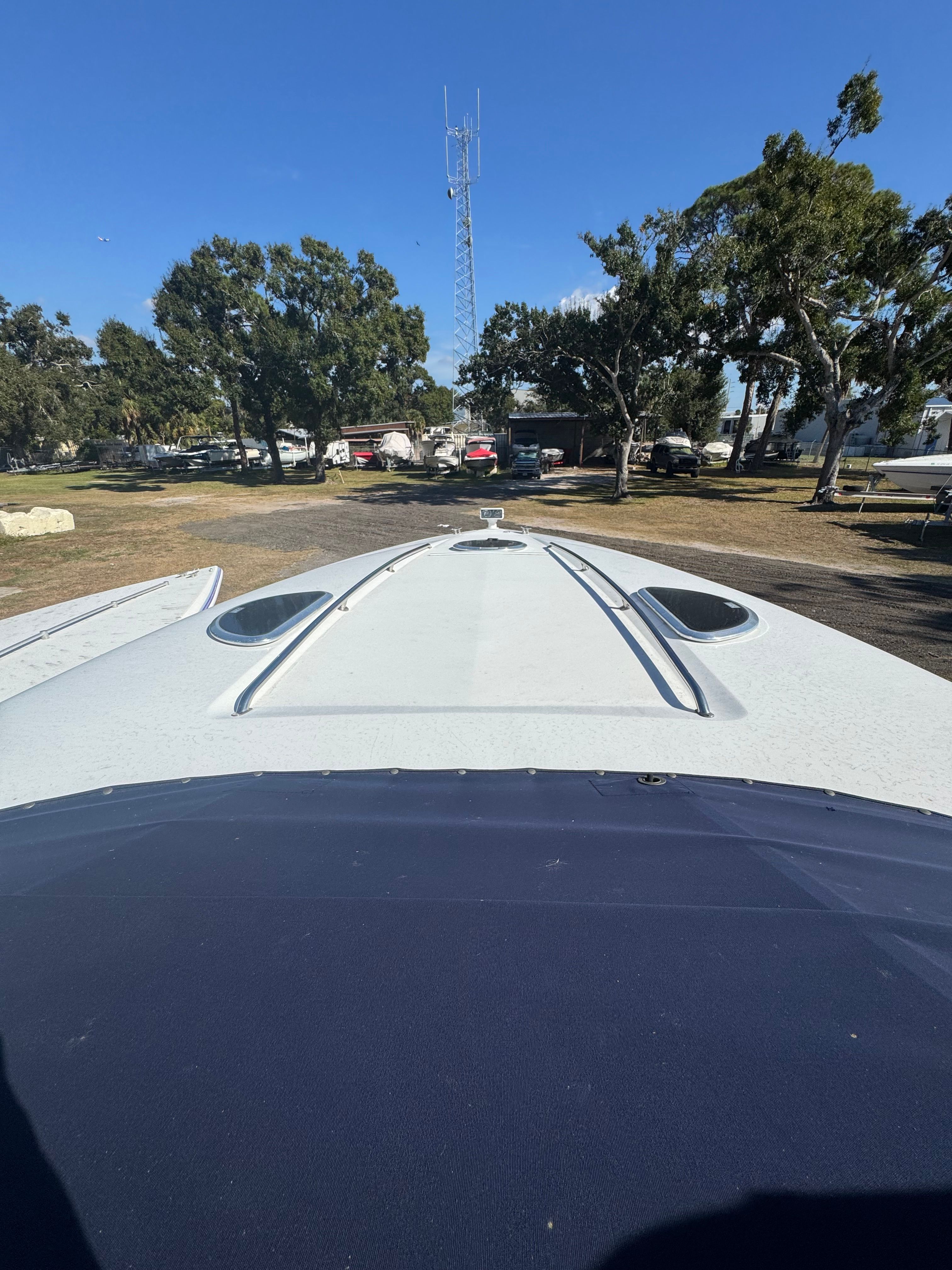 The 2003 Cobalt 360 is on land, surrounded by trees and vehicles.