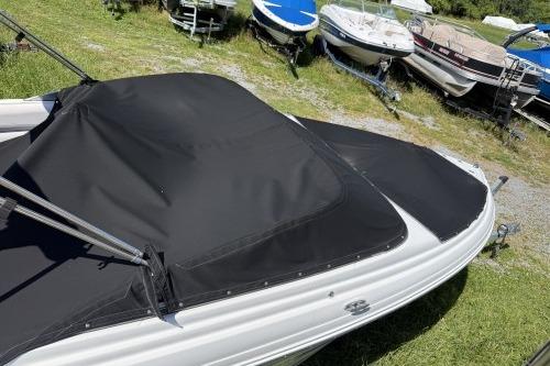 2012 Crownline 215 SS boat with black cover, parked on grass near other boats.