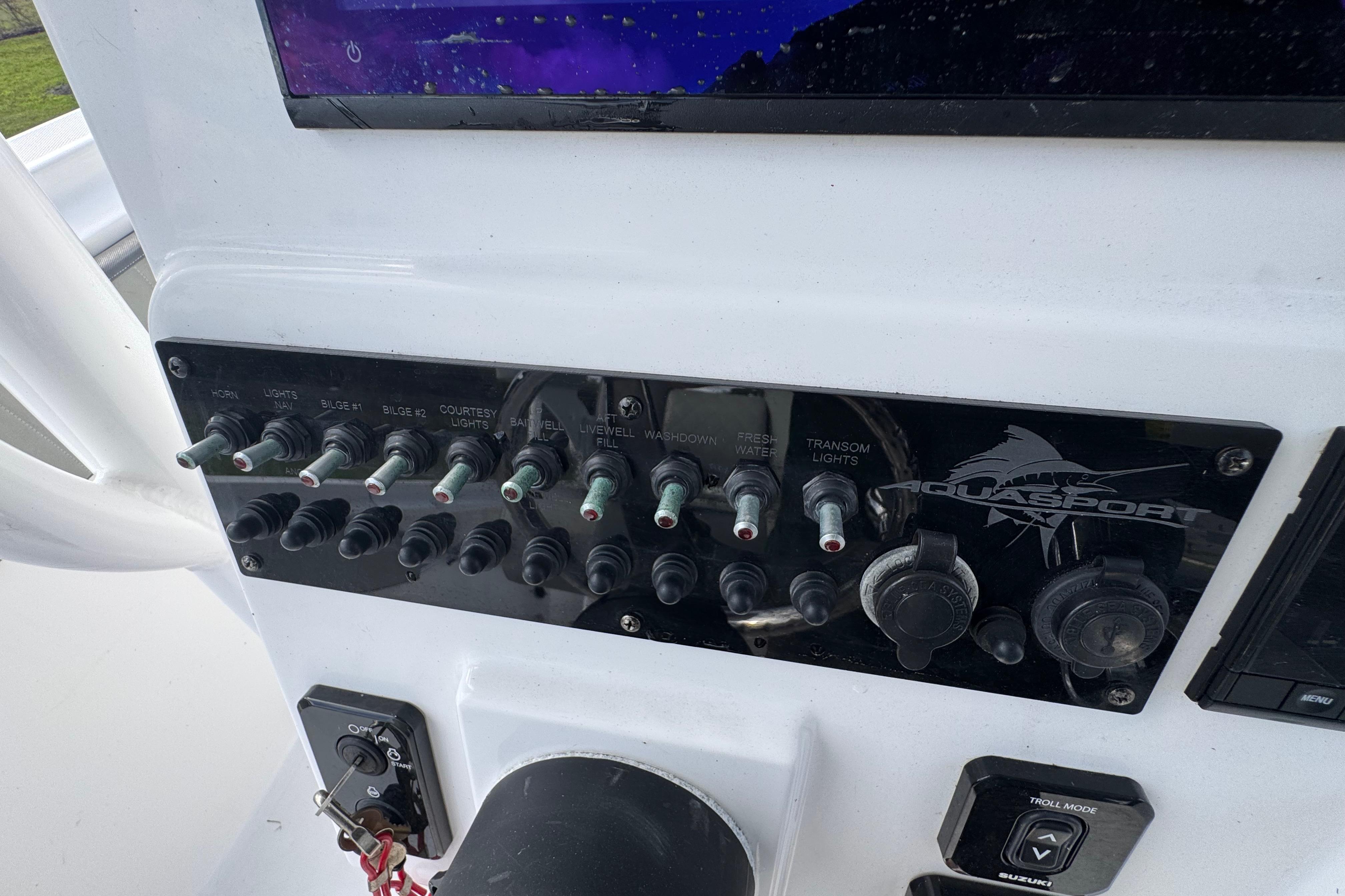 Control panel of 2022 Aquasport 2500 Center Console boat with switches and dials.