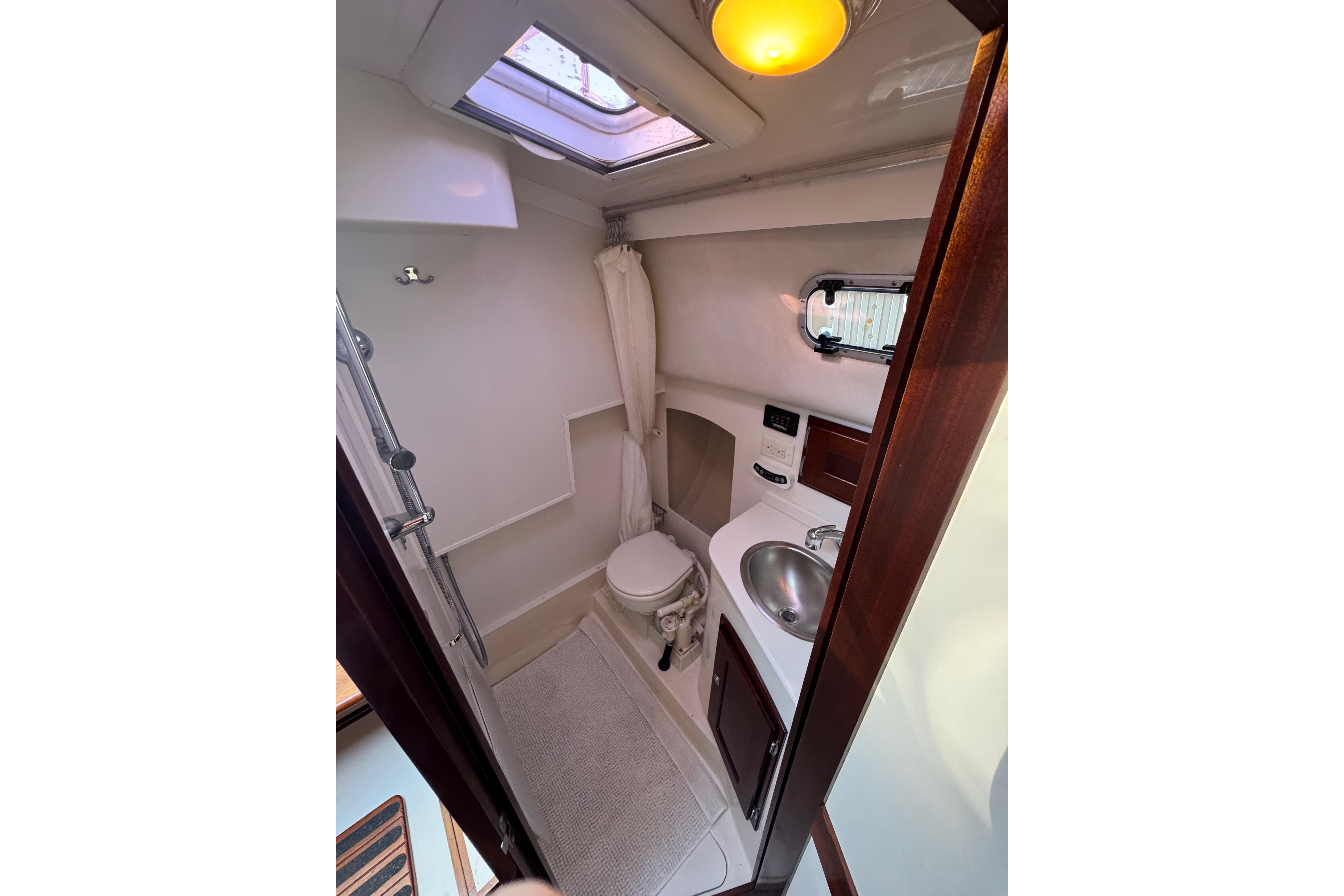 Compact bathroom in 2006 Shannon Shoalsailer yacht with skylight and modern fixtures.