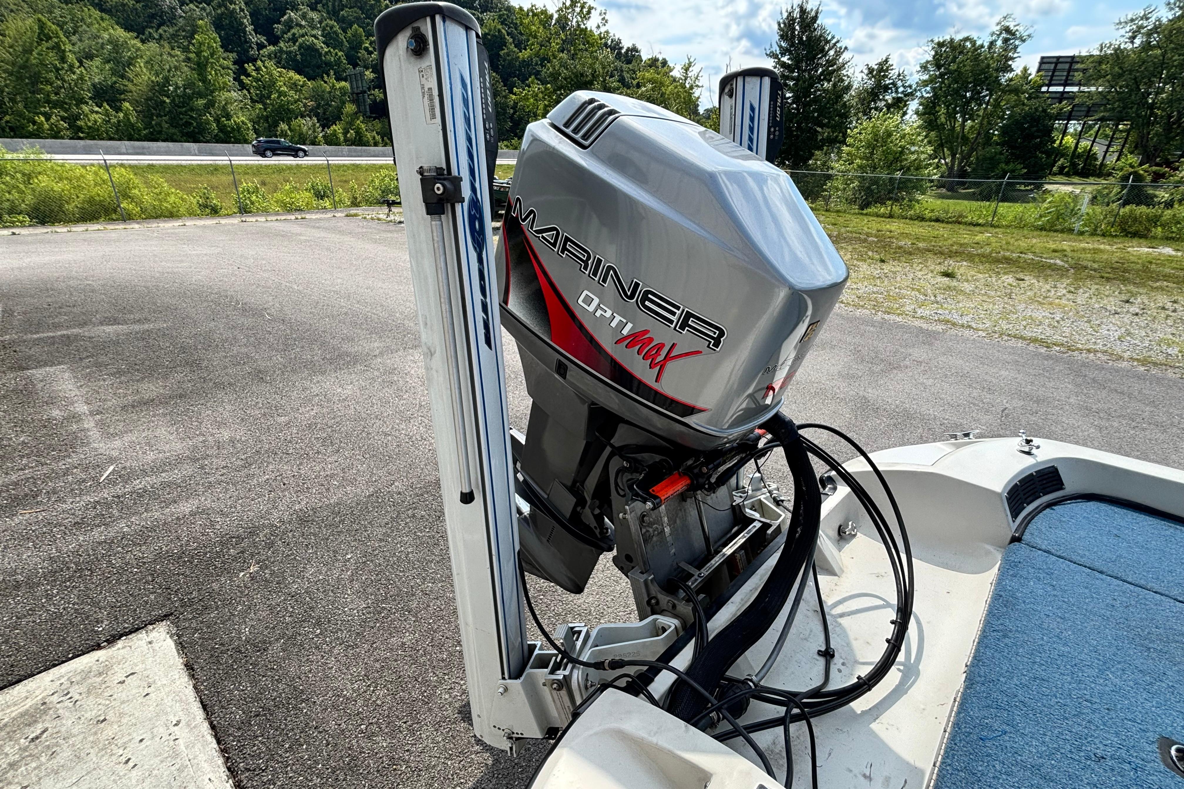 1991 Ranger 461VS boat with Mariner Optimax outboard motor, parked on asphalt near greenery.