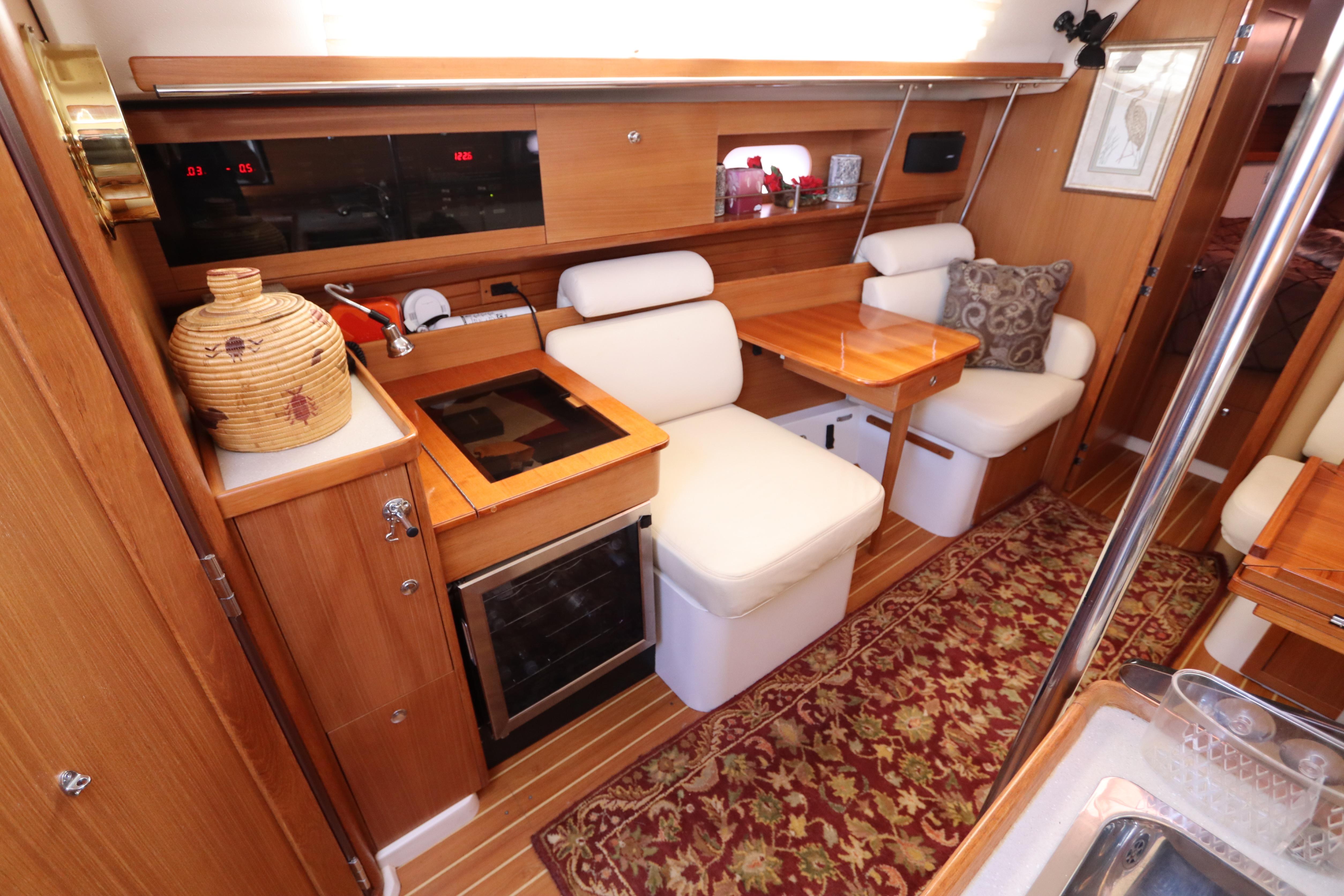 Interior of 2011 Catalina 355 sailboat with cozy seating and wooden cabinetry.