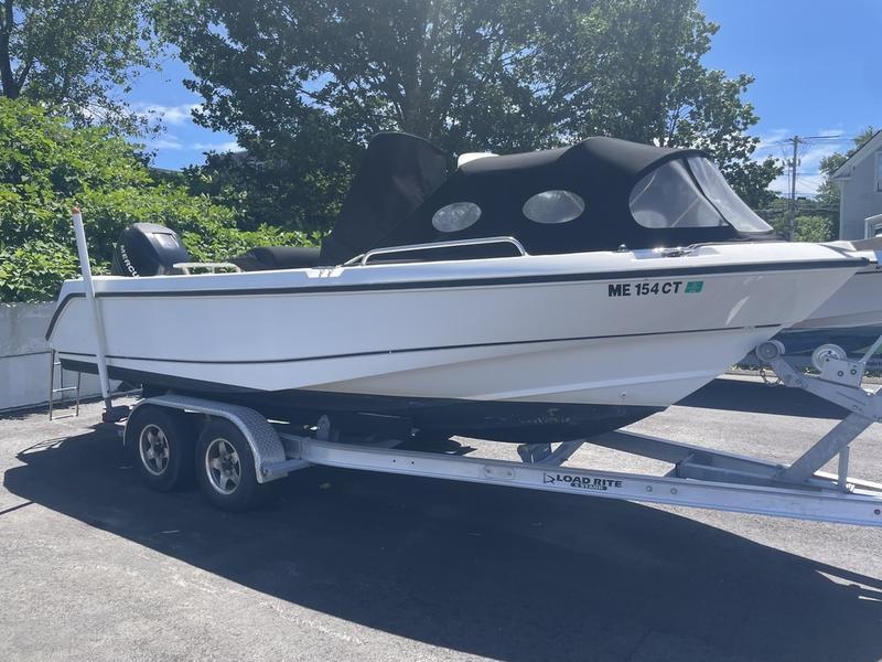 2006 Boston Whaler 210 Outrage boat on trailer, covered, parked outdoors.