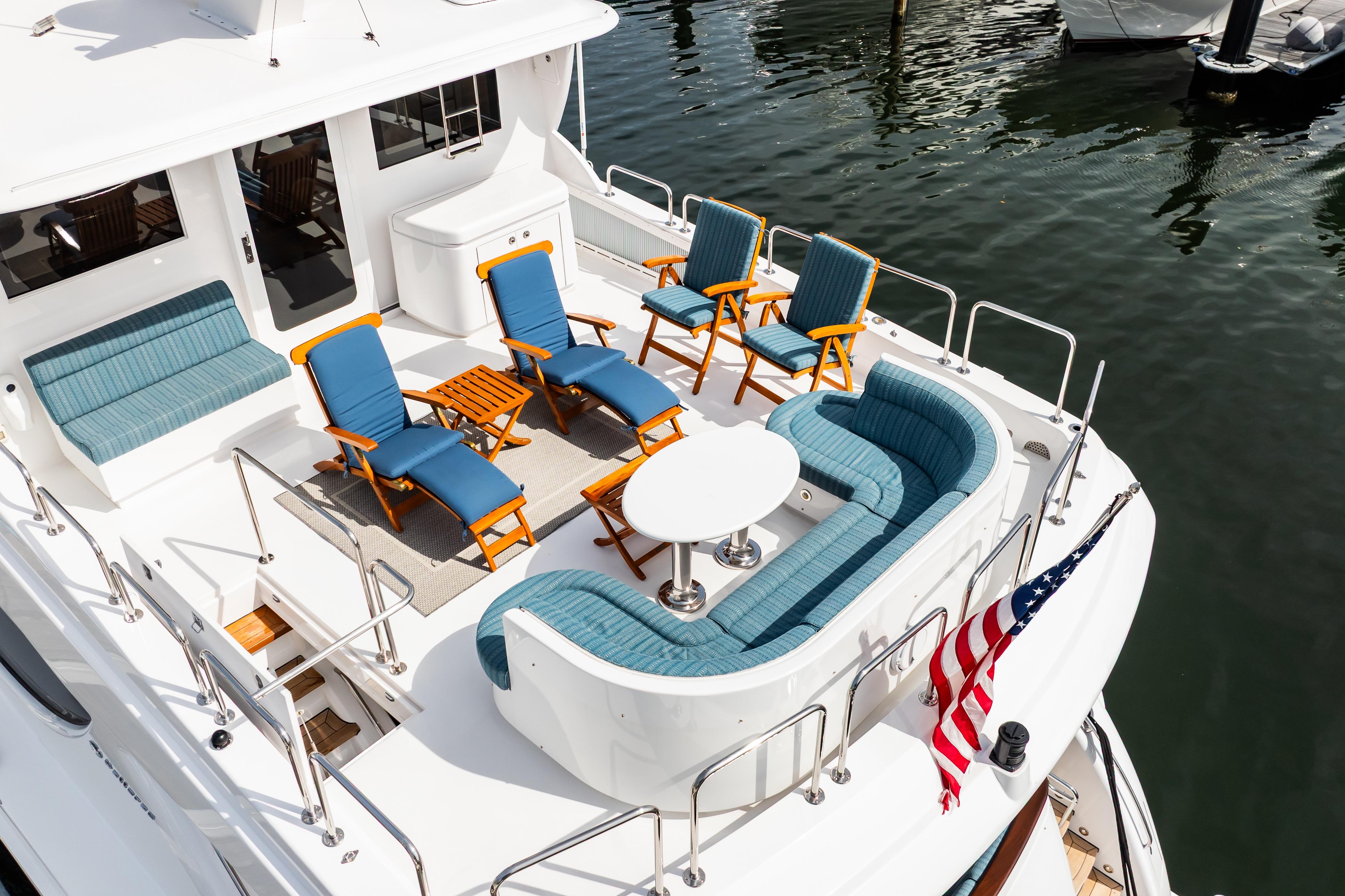 Luxurious 2012 Hatteras 80 Motor Yacht deck with elegant seating and American flag.