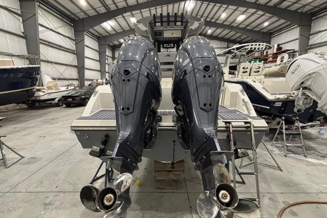2026 Cobia 245 Center Console boat with dual outboard engines in a storage facility.