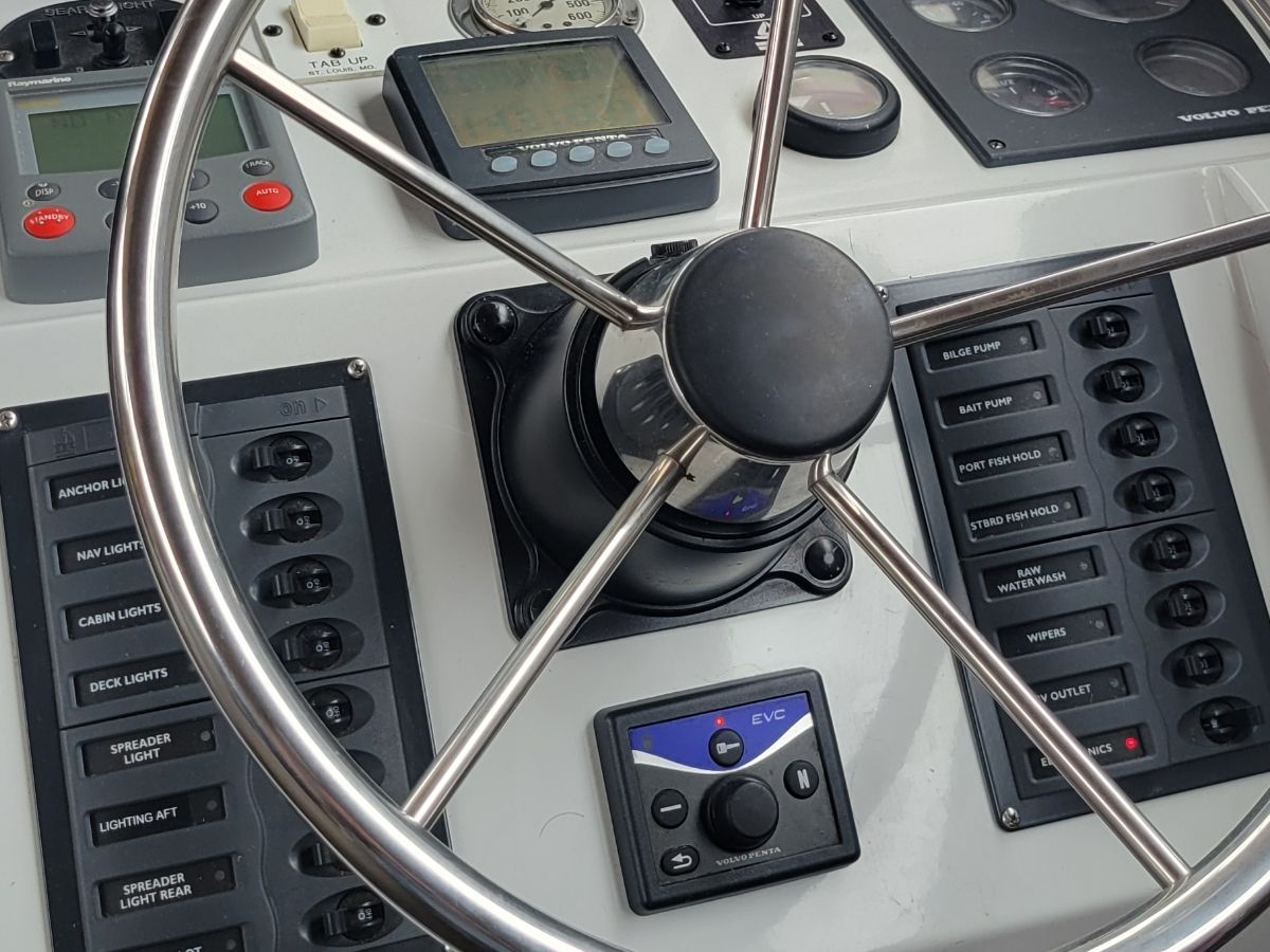 The image shows a boat's helm with various instruments and switches.