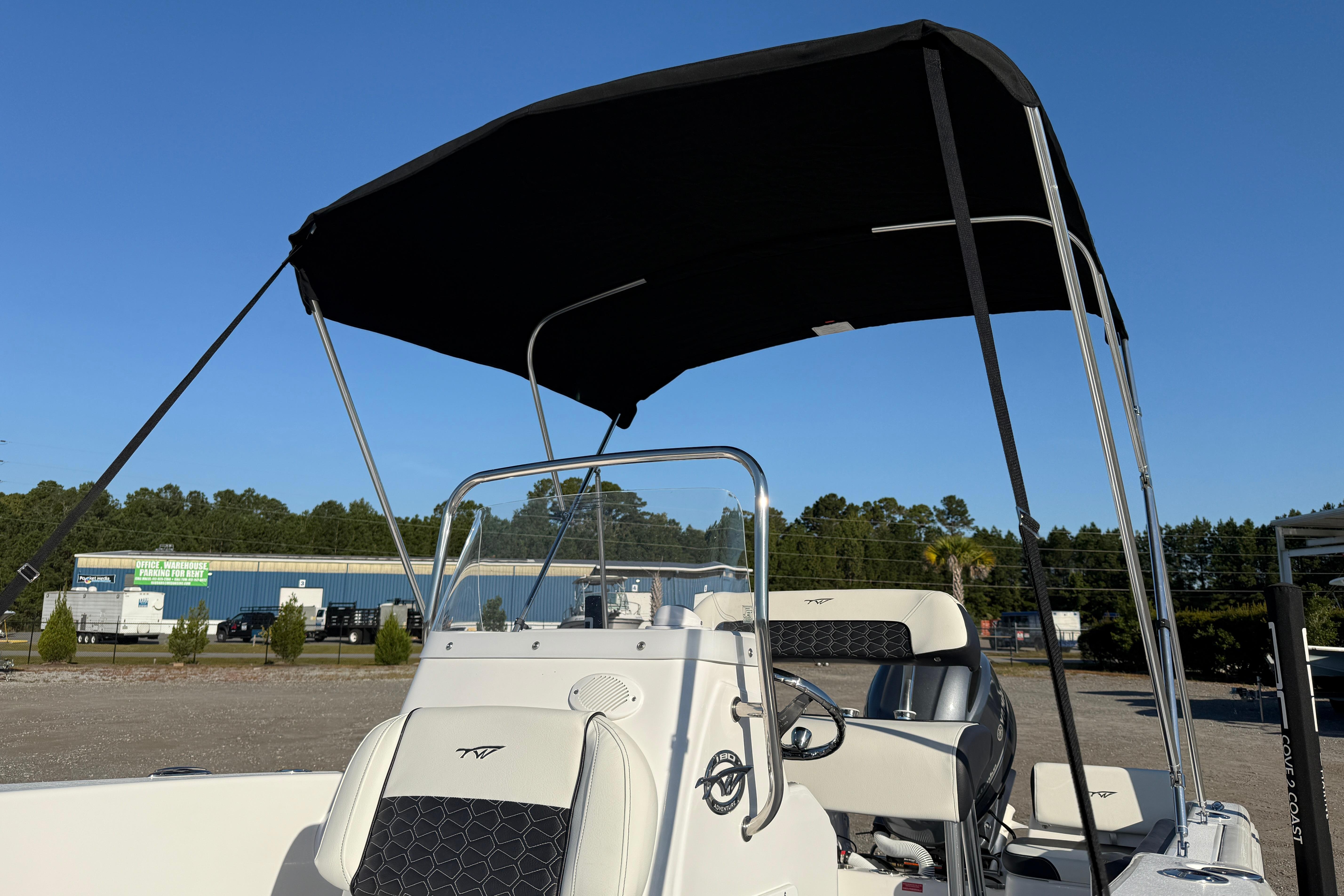 2026 Tidewater 180 CC Adventure boat with canopy, parked outdoors under clear blue sky.