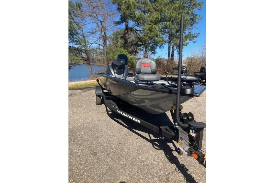 2026 Tracker Pro Team 175 boat on trailer near a lake, surrounded by trees.