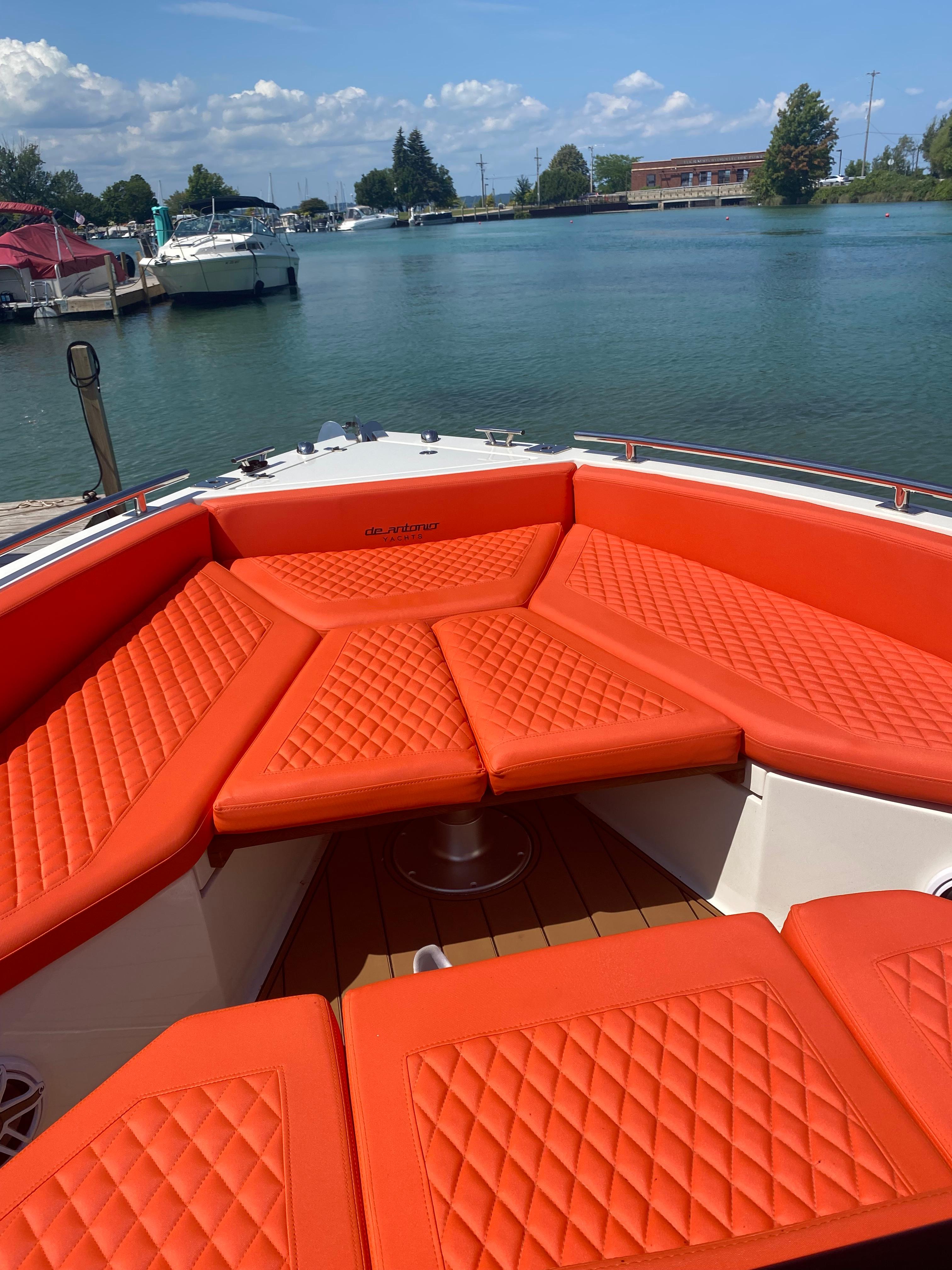 2020 De Antonio Yachts D 28 with orange seating, docked by a serene lake.
