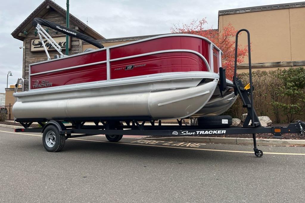2026 Sun Tracker Party Barge 18 DLX pontoon boat on trailer, parked outdoors.