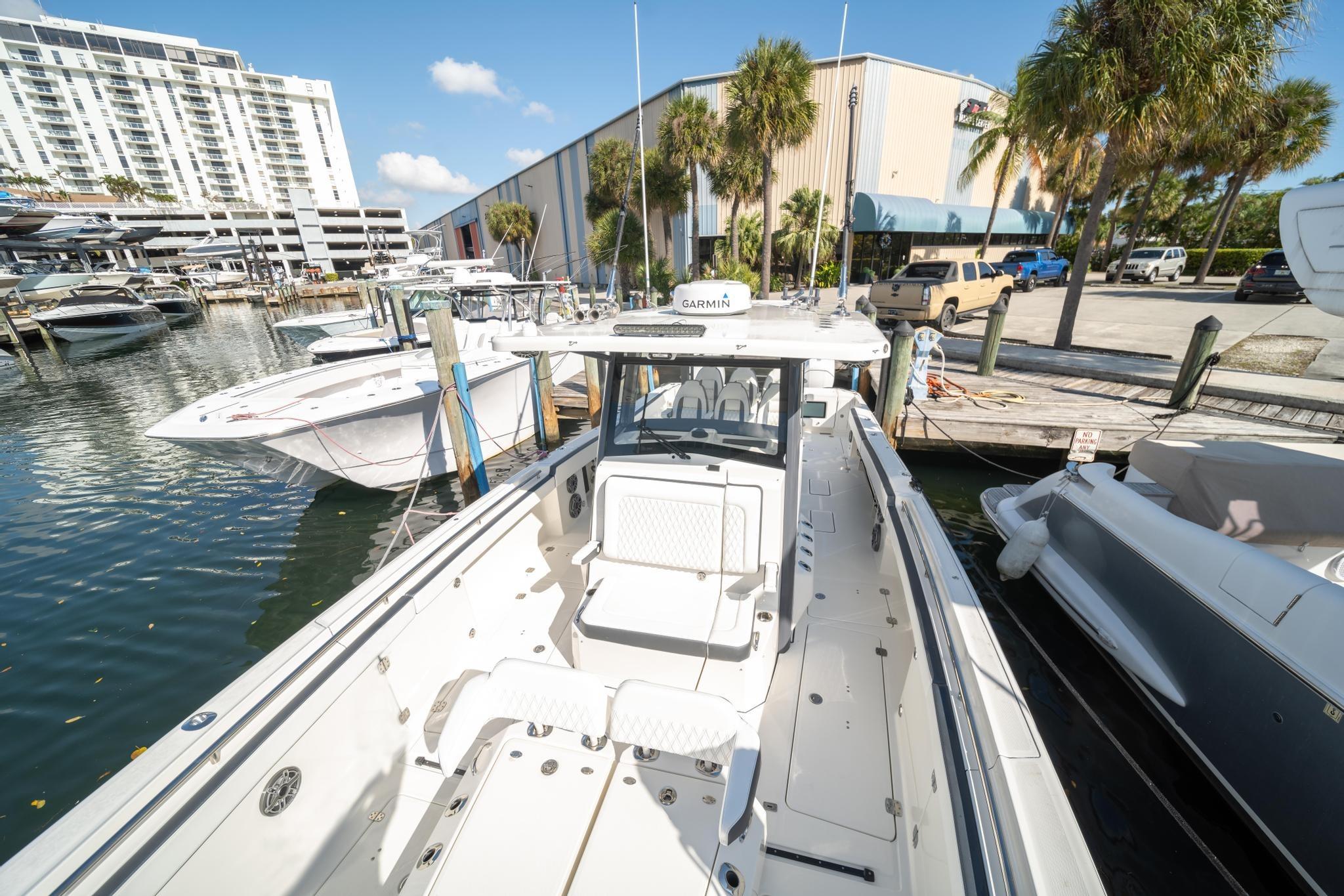 2022 World Cat 400 CC-X boat docked at marina with palm trees and buildings.