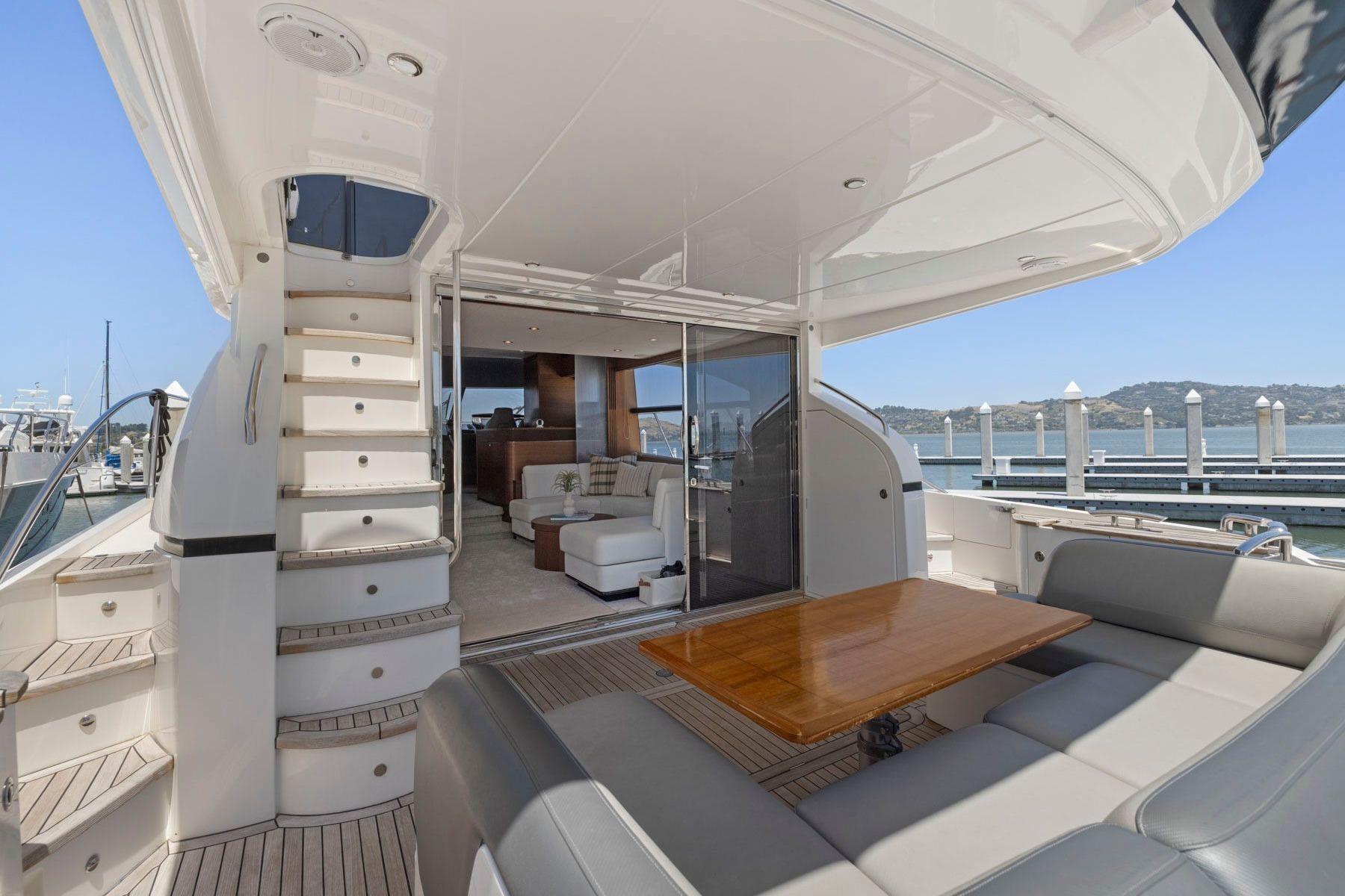 Luxurious 2015 Princess 60 Flybridge Motor Yacht with elegant outdoor seating and scenic marina view.