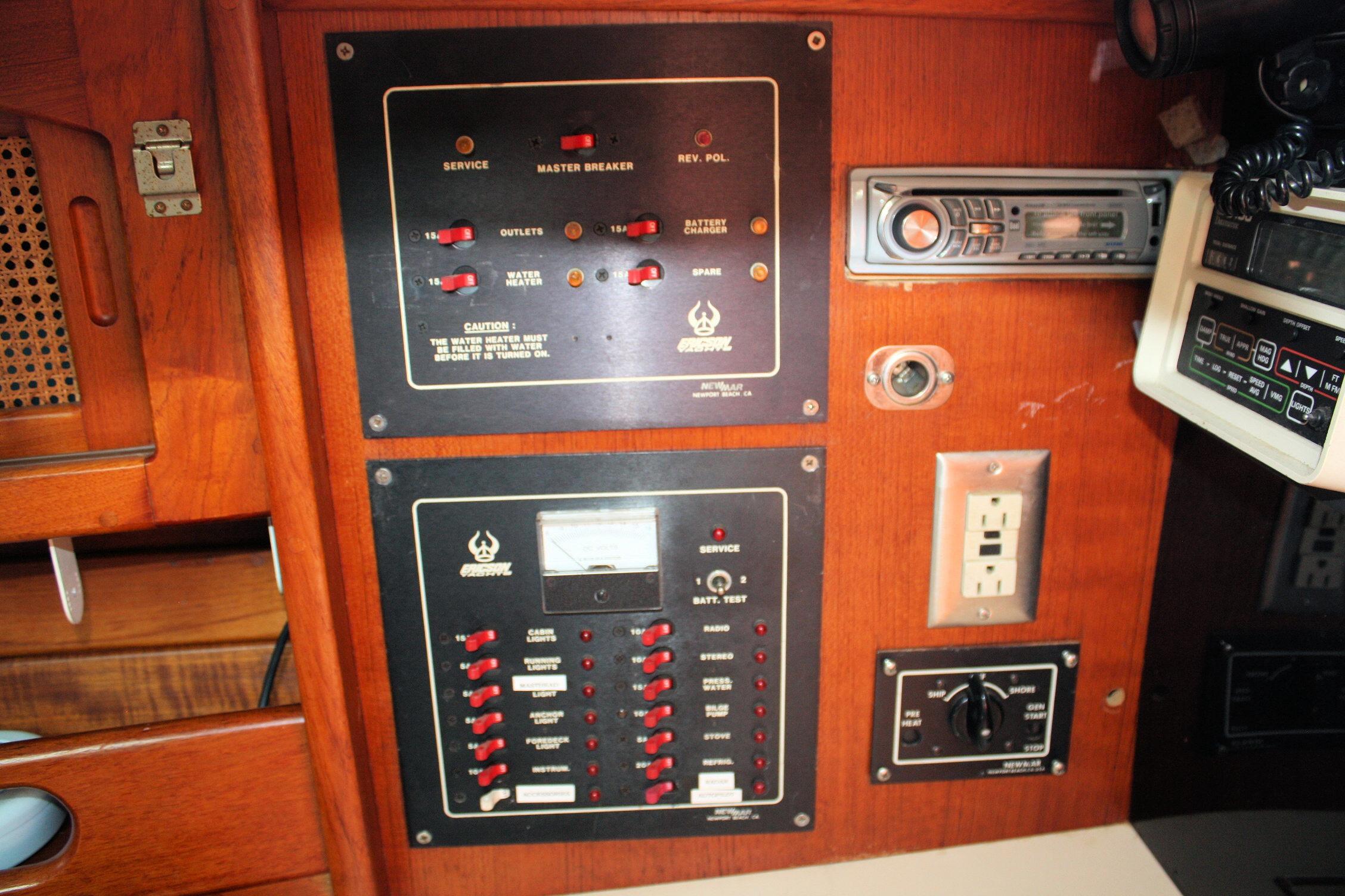 Electrical control panel on a 1987 Ericson 38-200 sailboat, featuring switches and outlets.