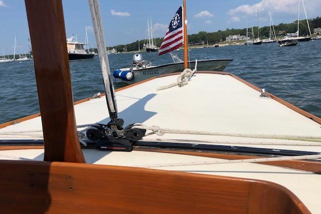 Sailing on a 1963 Cape Cod Shipbuilding Shields boat with American flag in harbor.