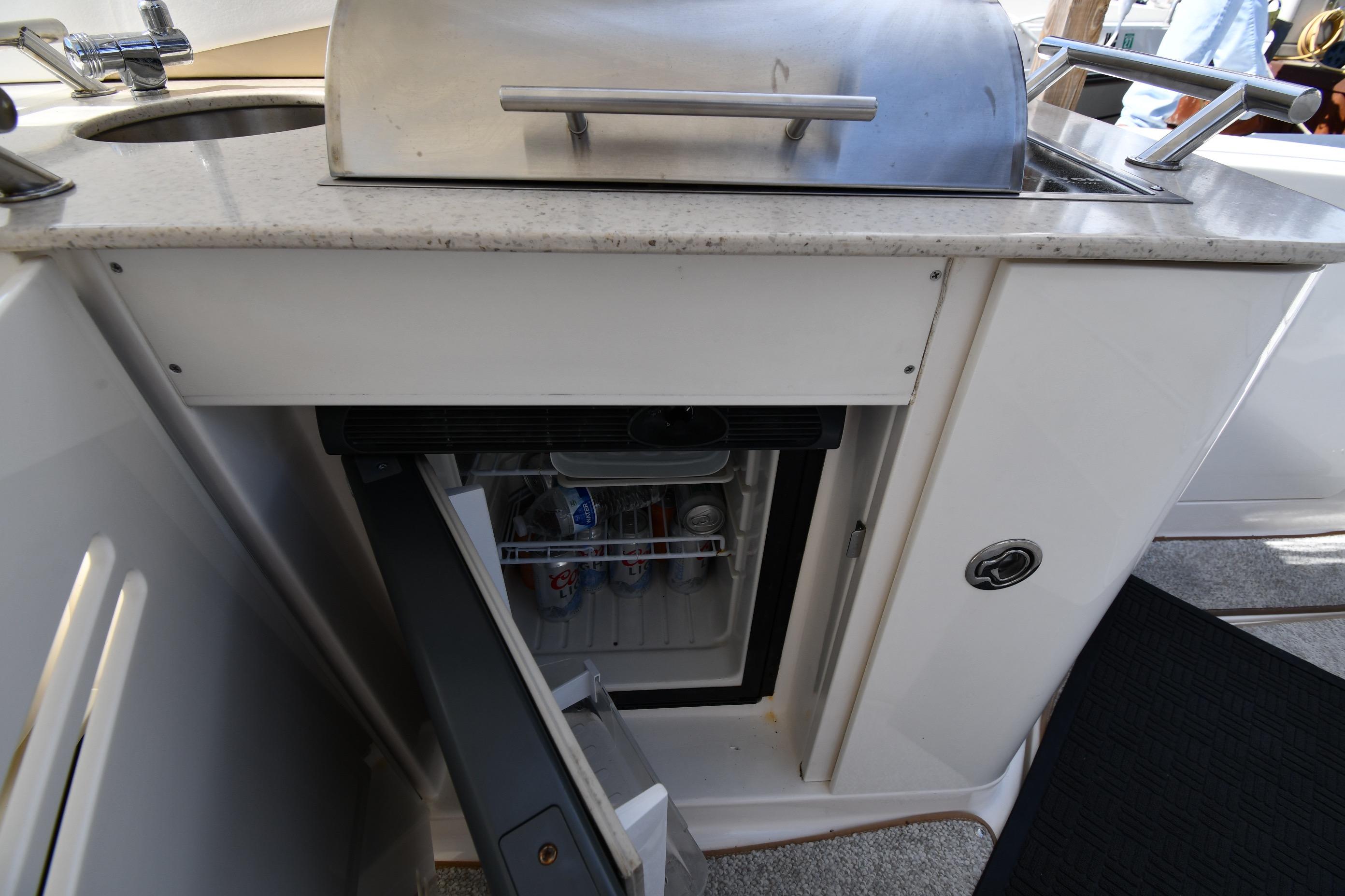 Outdoor kitchenette on a 2008 Sea Ray Sundancer 350 yacht with a mini fridge and grill.