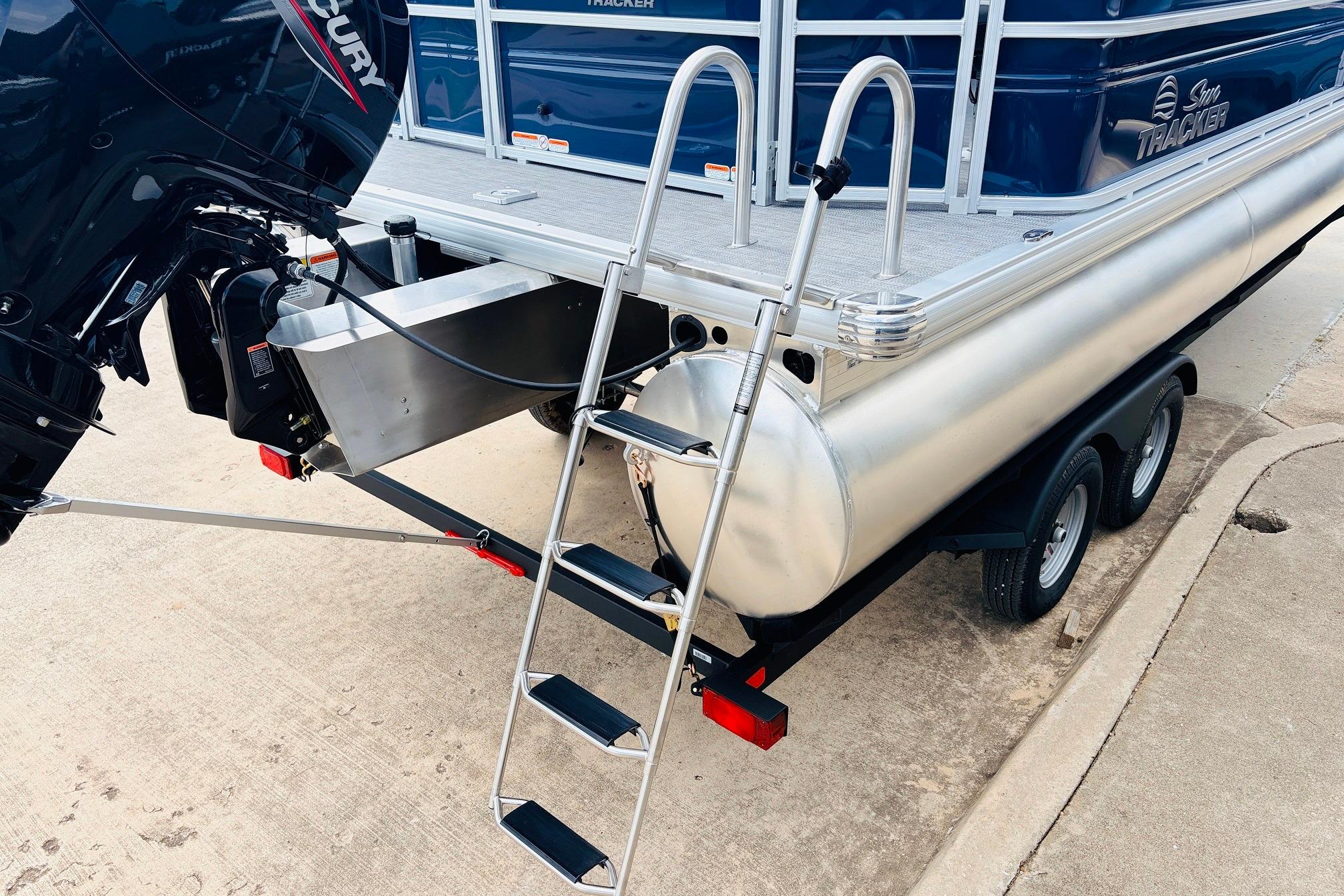 2026 Sun Tracker SportFish 22 DLX pontoon boat on trailer with outboard motor and ladder.