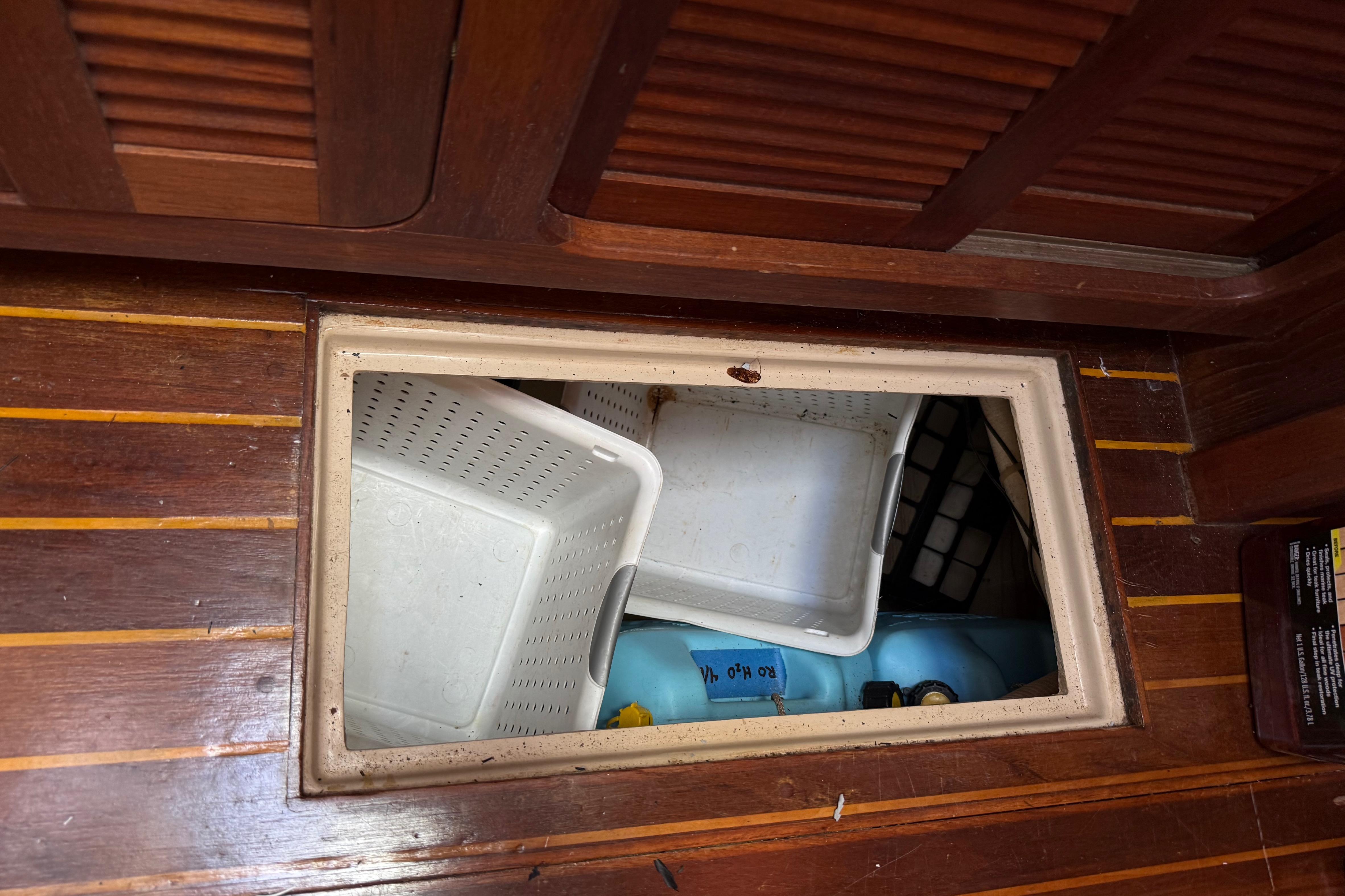 Storage compartment on 1984 Stamas 44 boat with plastic bins and containers.